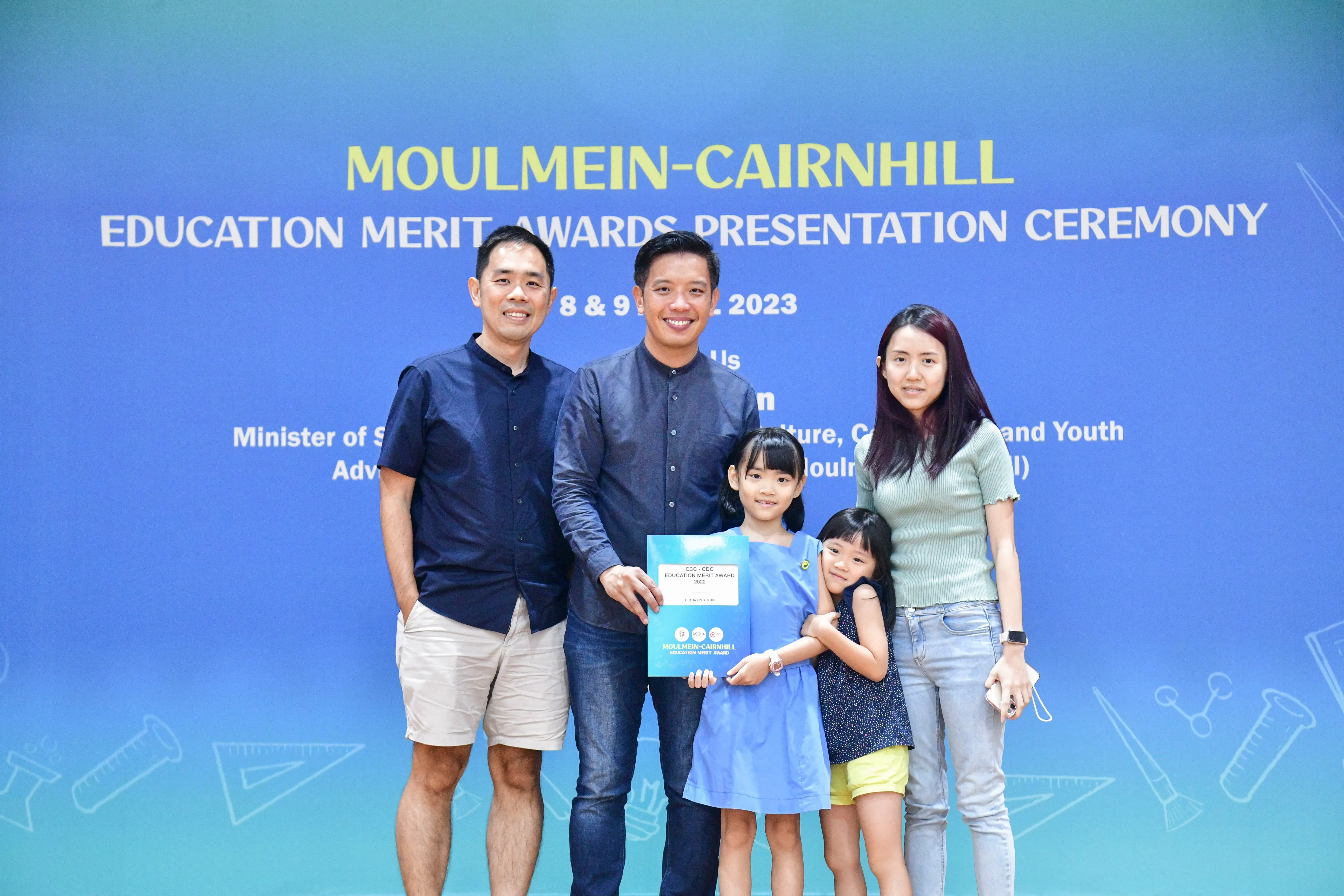 Two men, a woman, and two young girls pose with an award at the Moulmein-Cairnhill Education Merit Awards 2023.