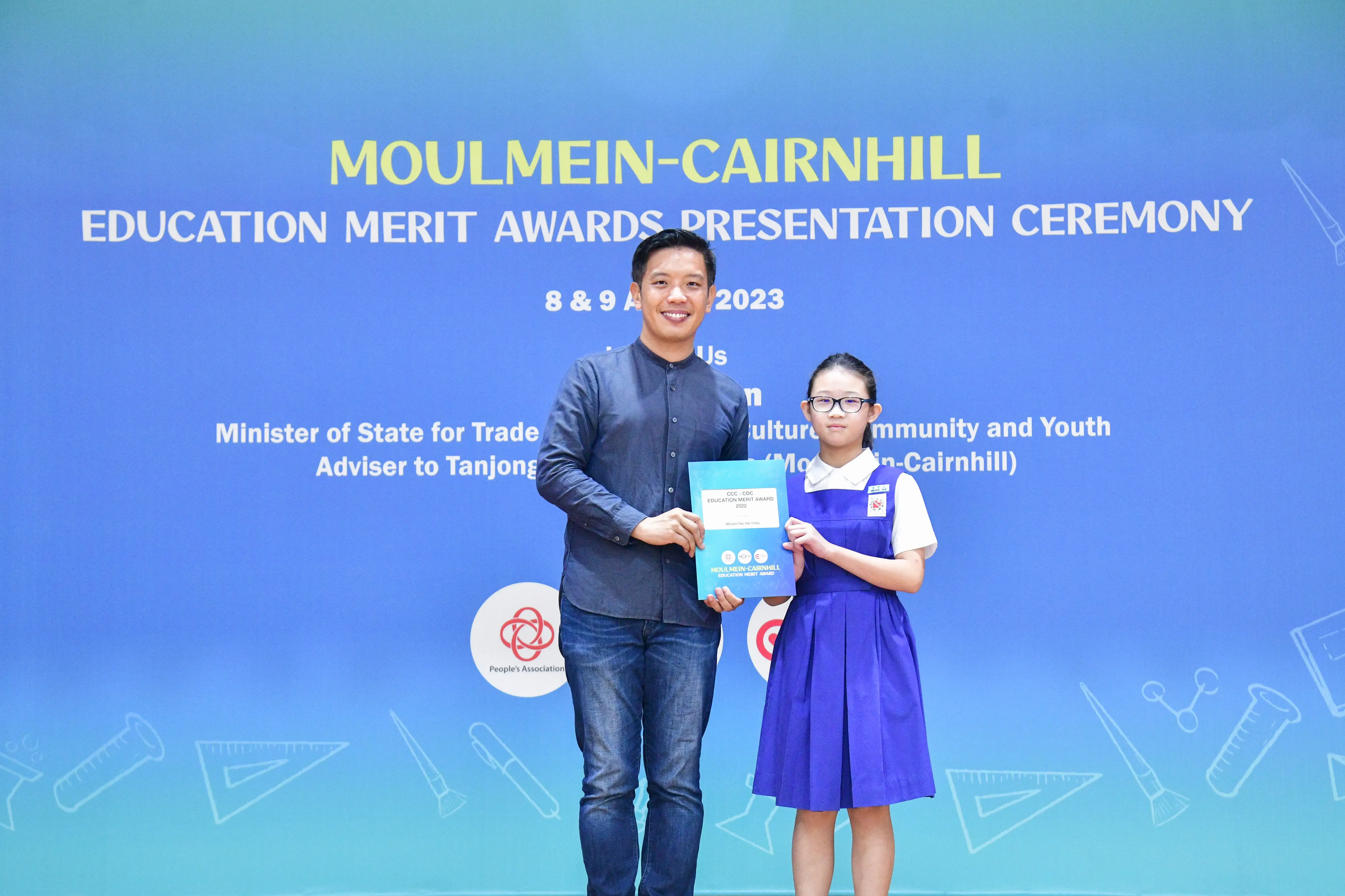 Man and young girl holding an award certificate at Moulmein-Cairnhill Education Merit Awards Ceremony 2023.