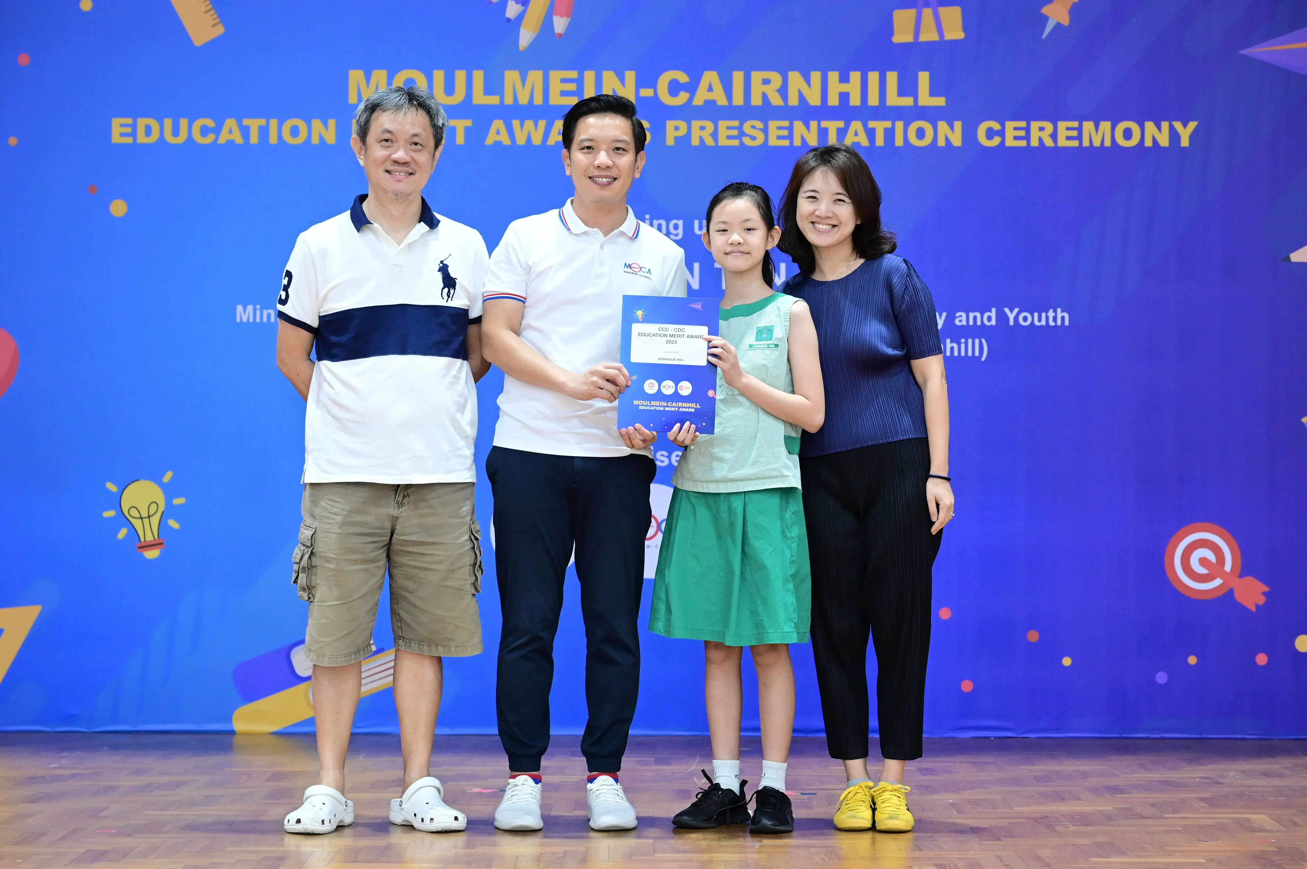 Four people pose with a certificate at the Moulmein-Cairnhill Education Merit Award Presentation Ceremony.