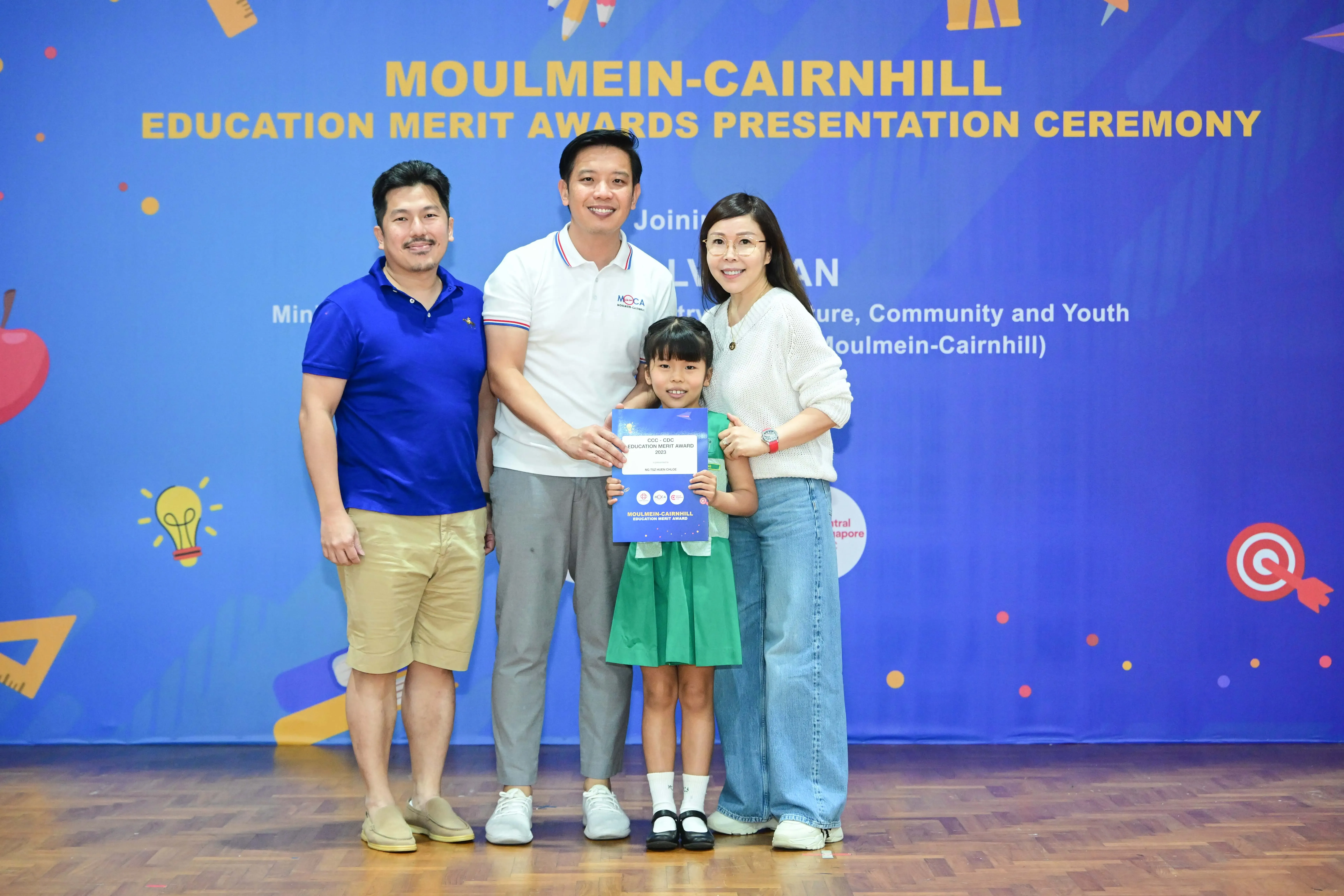 Three adults and a young girl holding a certificate pose at the Moulmein-Cairnhill Education Merit Awards ceremony.