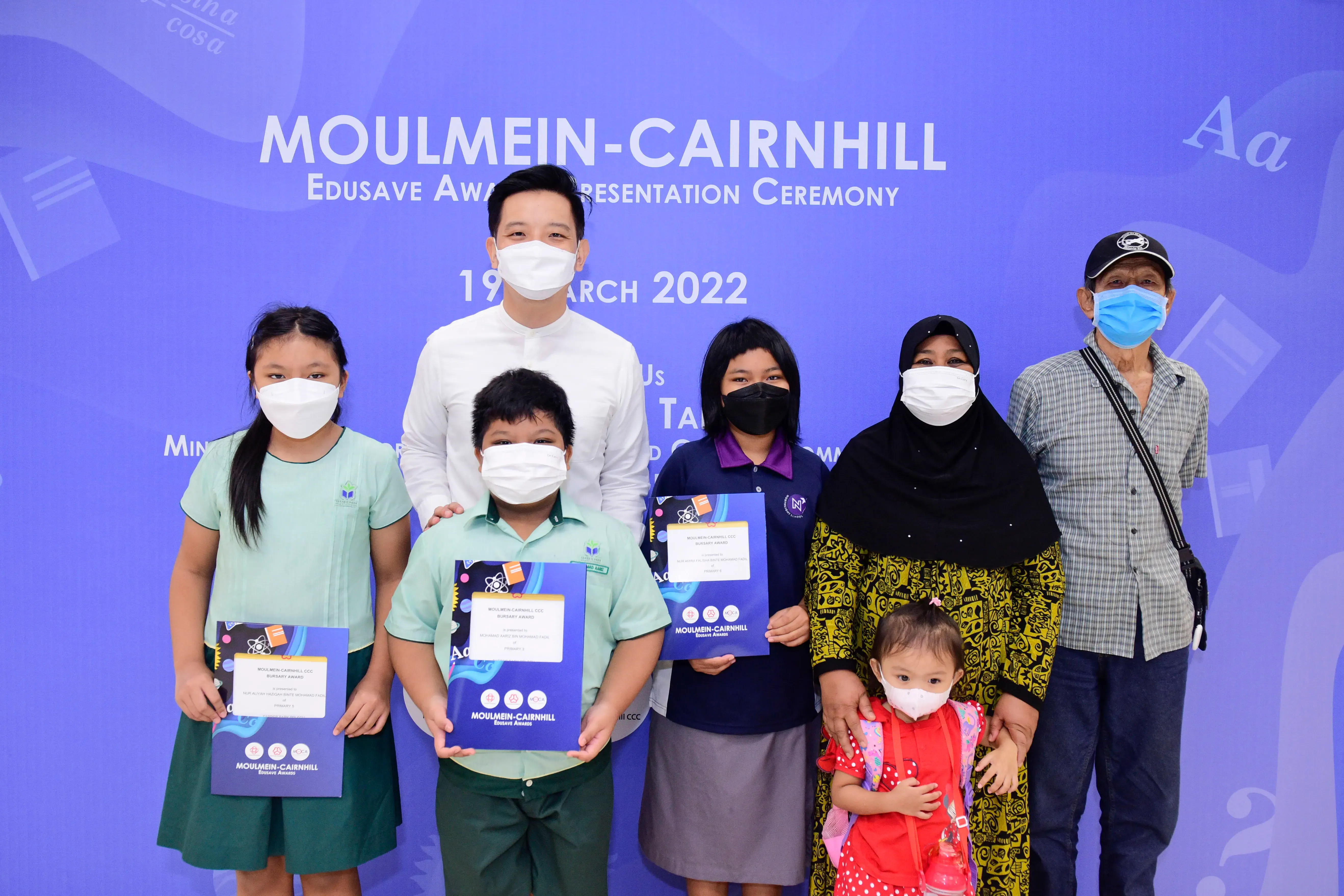 Group of masked people holding award certificates at the Moulmein-Cairnhill Edusave Award Ceremony, March 2022.