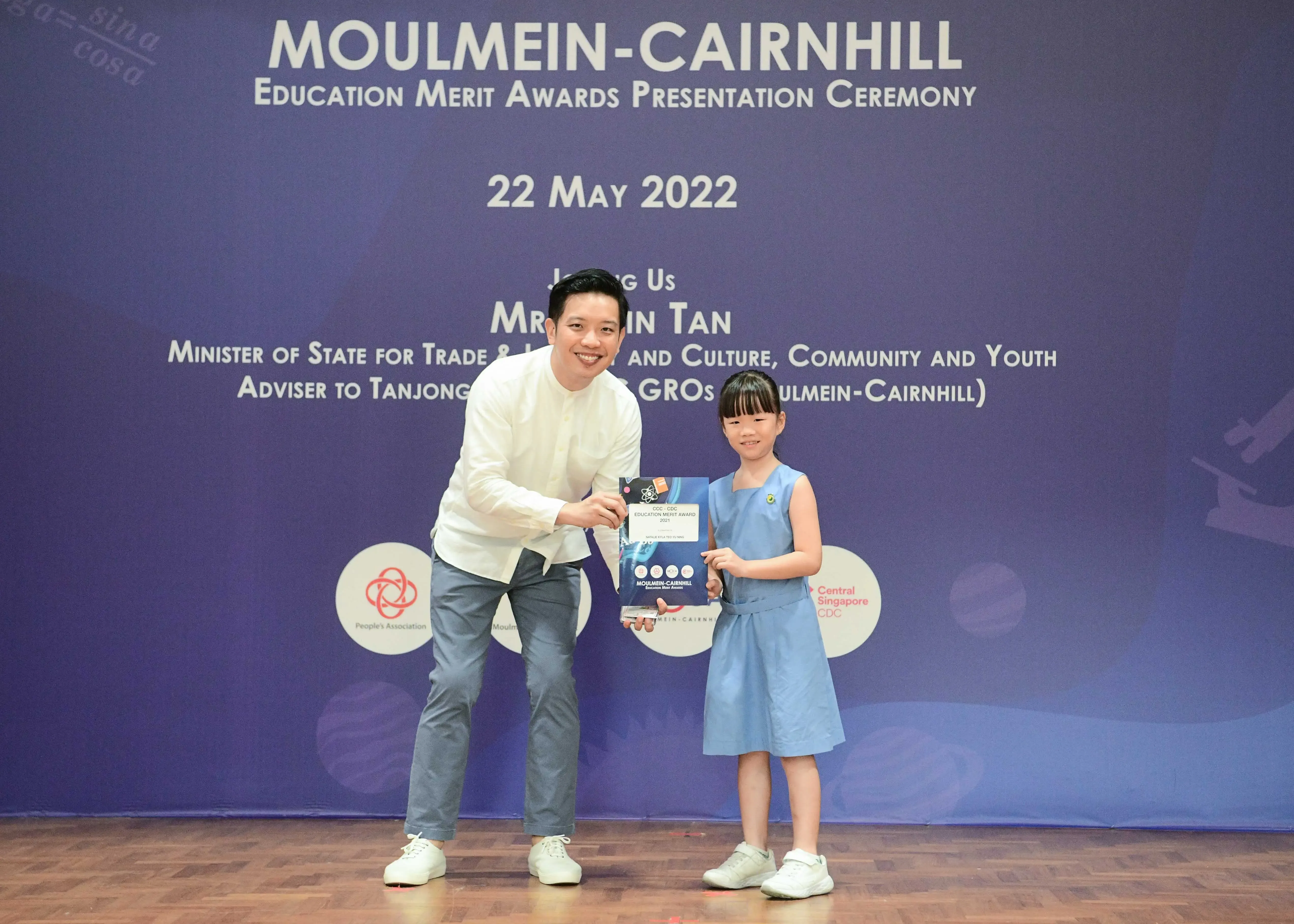 A man and a young girl hold an award certificate at the Moulmein-Cairnhill Education Merit Awards on 22 May 2022.