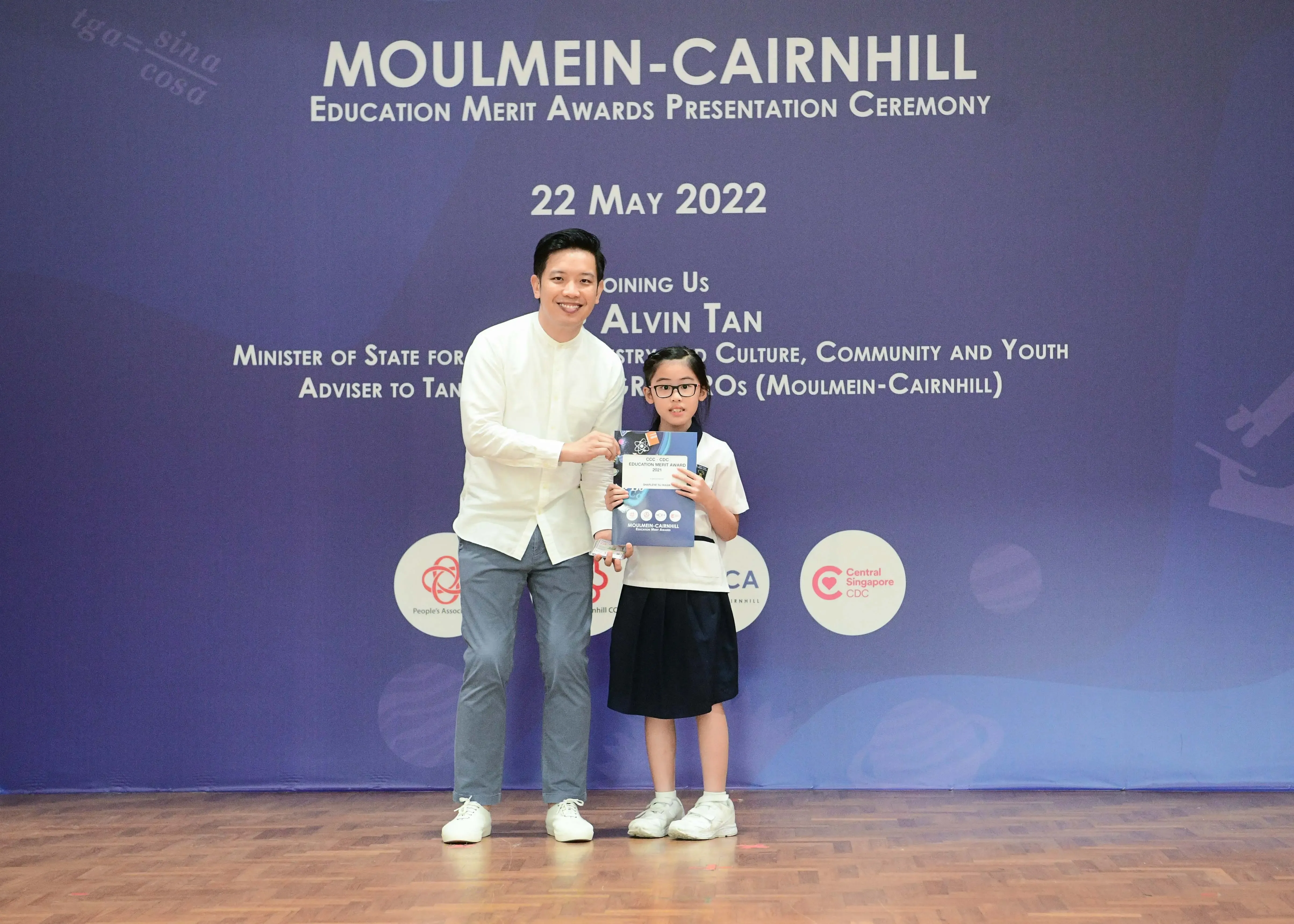 A man and a young girl pose together holding an award at the Moulmein-Cairnhill Education Merit Awards ceremony on 22 May 2022.