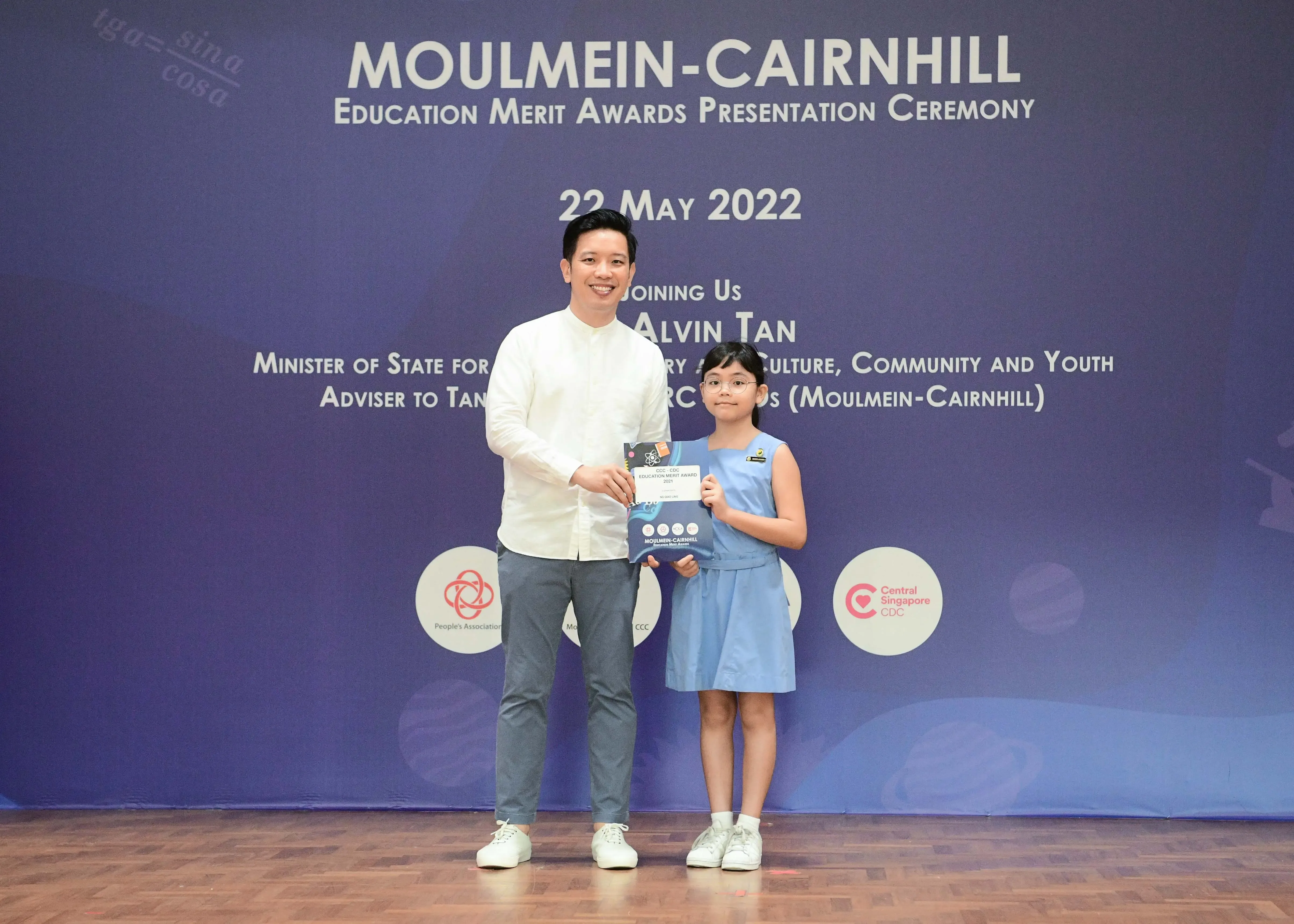 A man and a young girl pose holding an award at the Moulmein-Cairnhill Education Merit Awards on 22 May 2022.