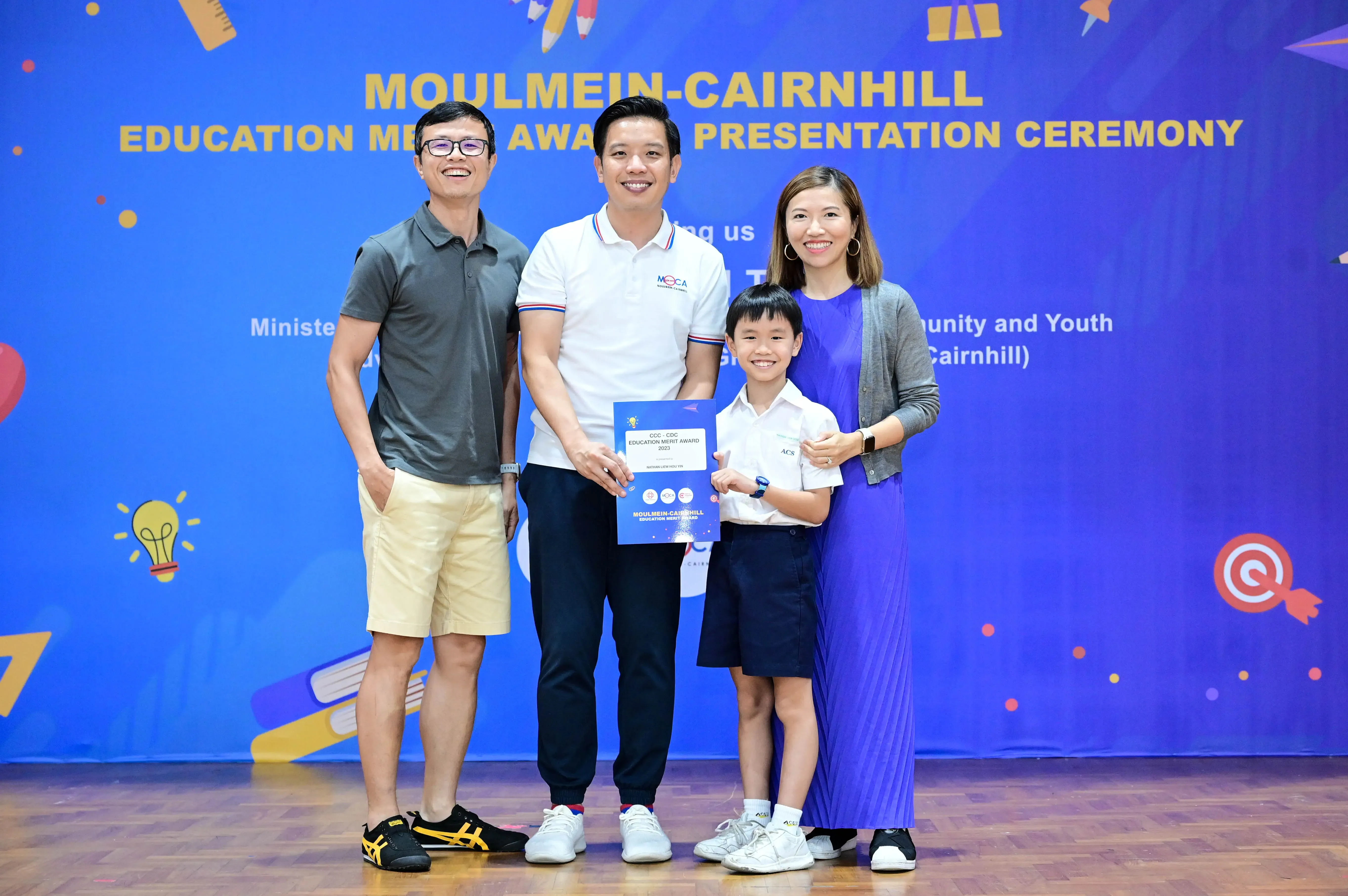 Three adults and a young boy pose with a certificate at the Moulmein-Cairnhill Education Merit Award Presentation Ceremony.