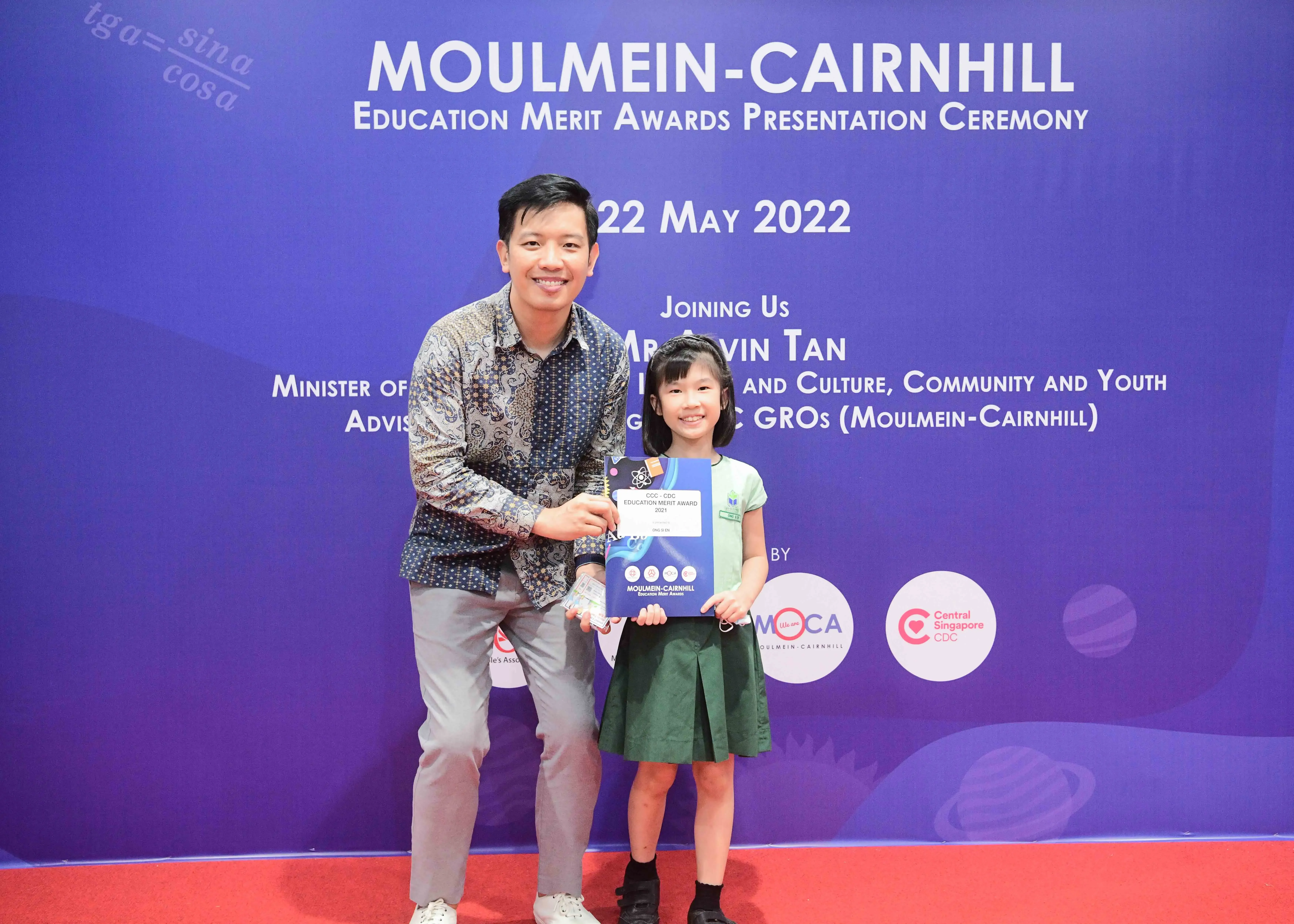 A man and a young girl hold an award certificate at the Moulmein-Cairnhill Education Merit Awards ceremony on 22 May 2022.