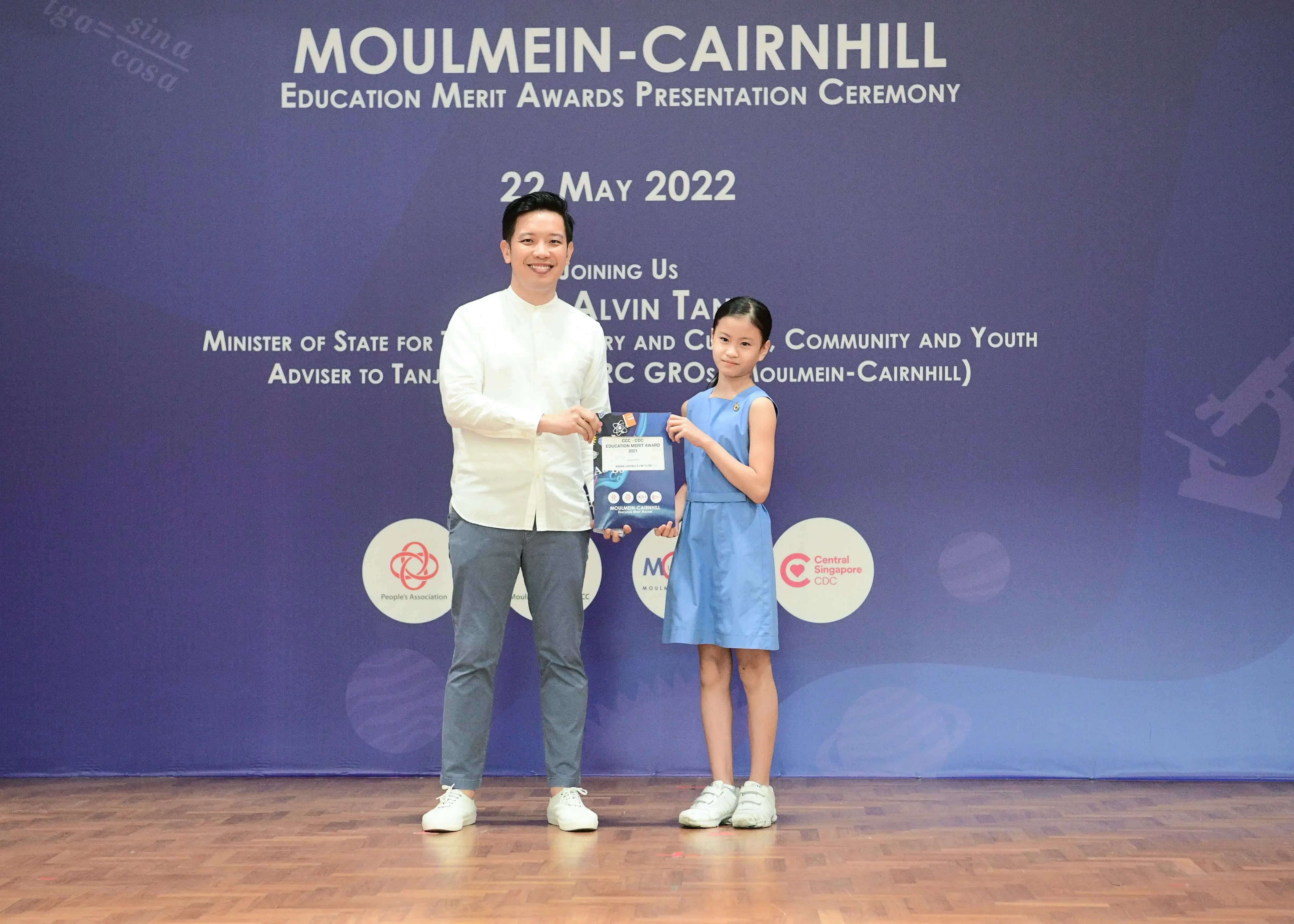 A man and a young girl hold an award together at the Moulmein-Cairnhill Education Merit Awards on 22 May 2022.