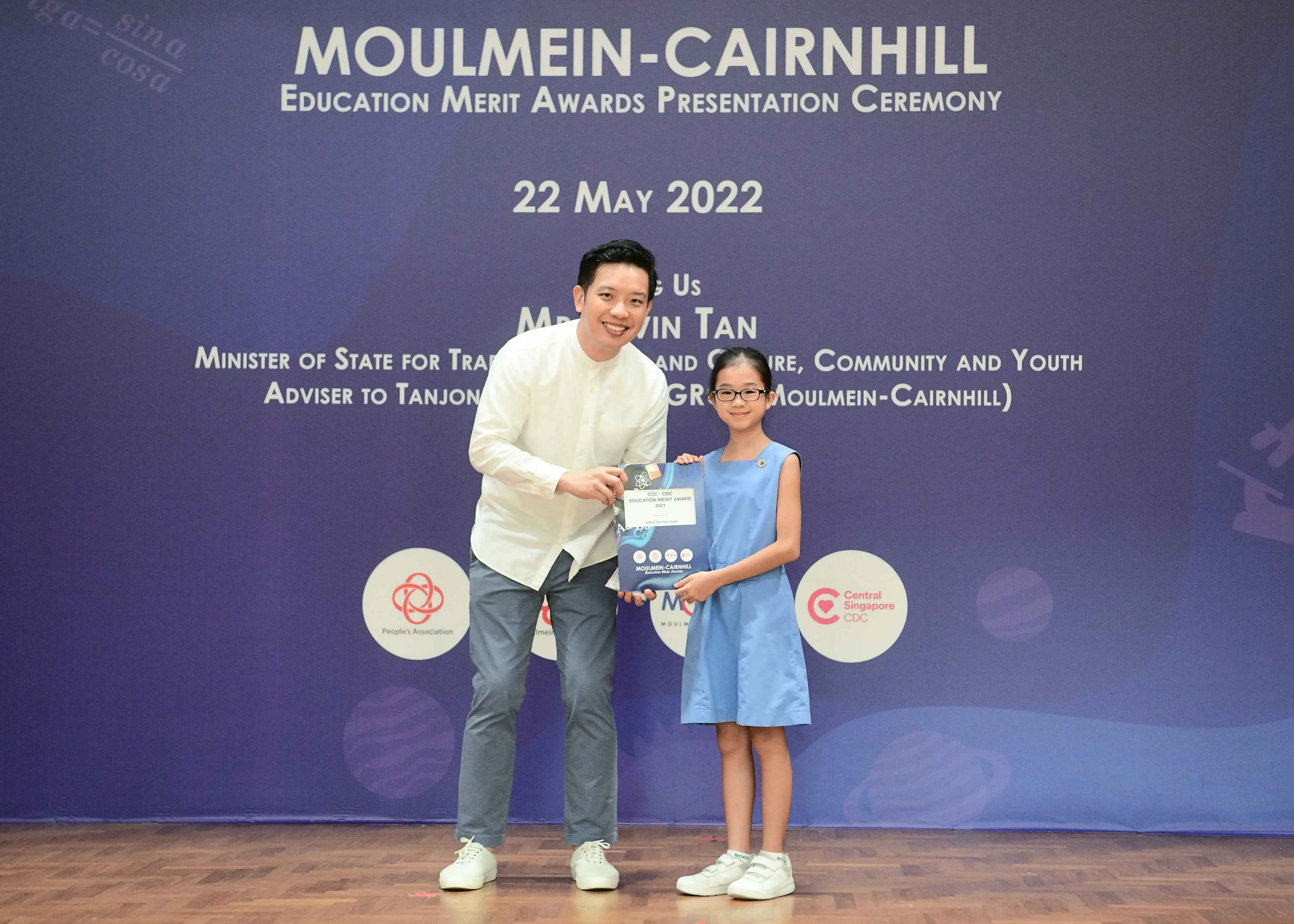 A man and a young girl hold an award certificate at the Moulmein-Cairnhill Education Merit Awards on 22 May 2022.