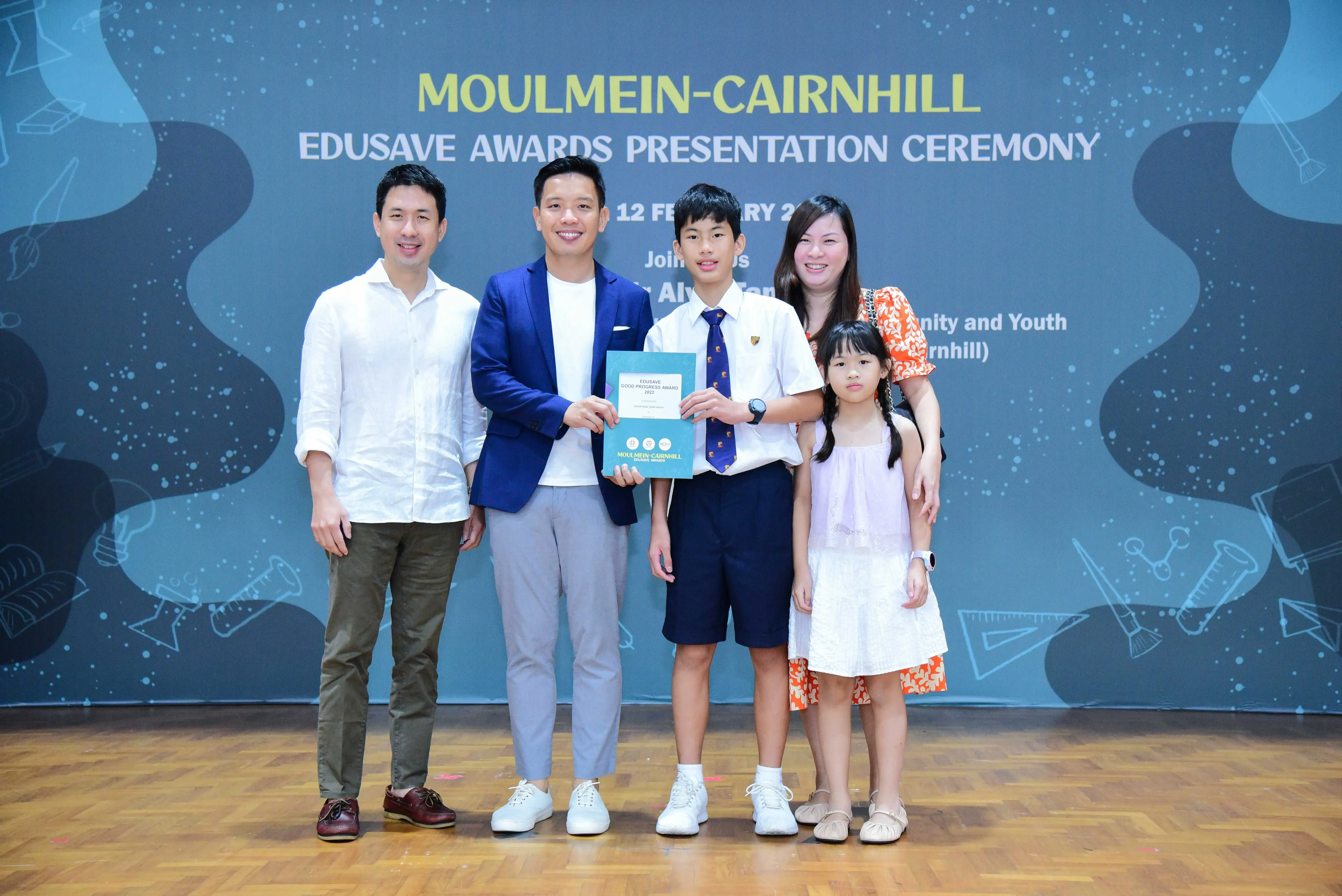 A boy in school uniform receives an award certificate at the Moulmein-Cairnhill Edusave Awards Presentation Ceremony.