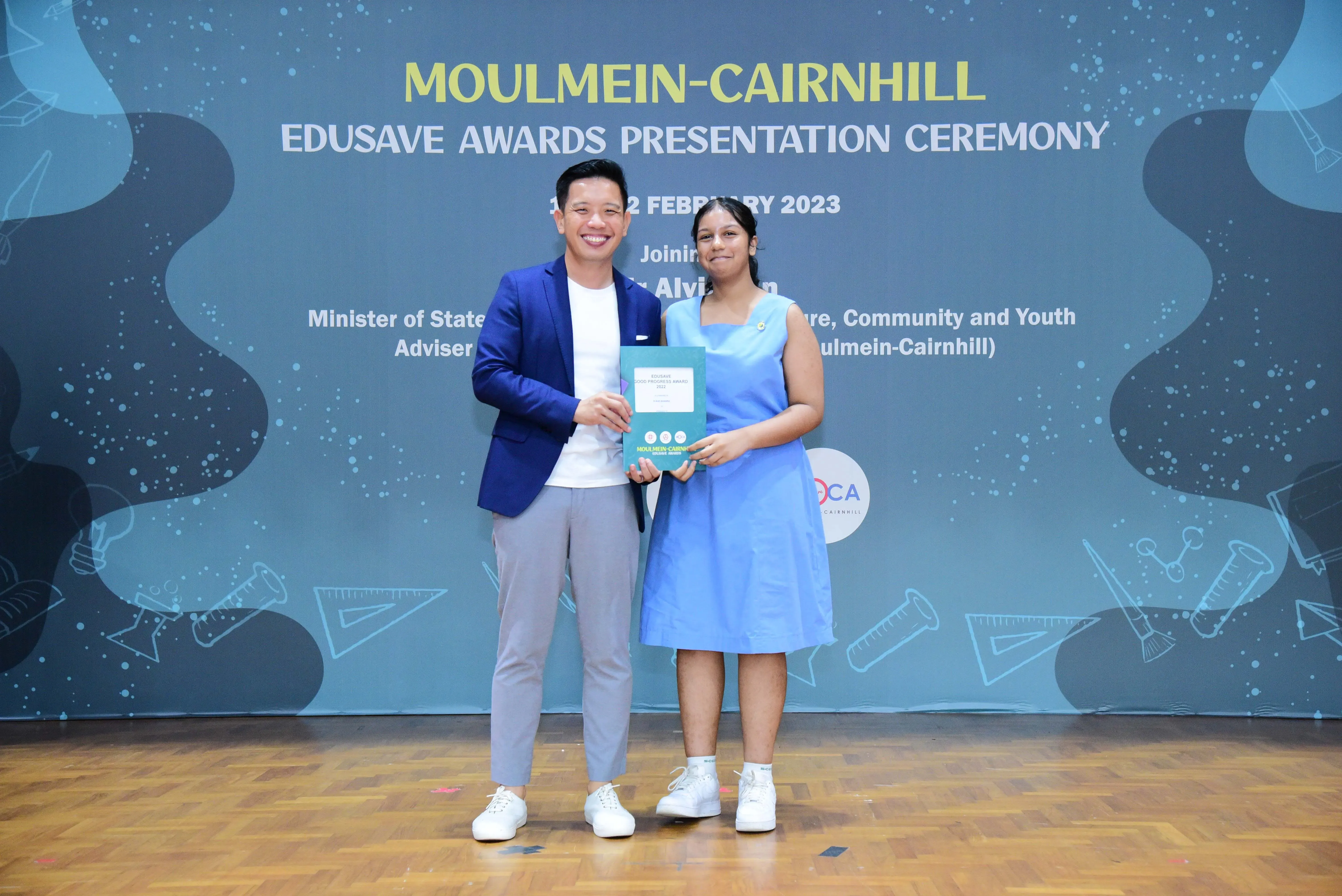 Two people hold an award certificate at the Moulmein-Cairnhill Edusave Awards Presentation Ceremony, February 2023.