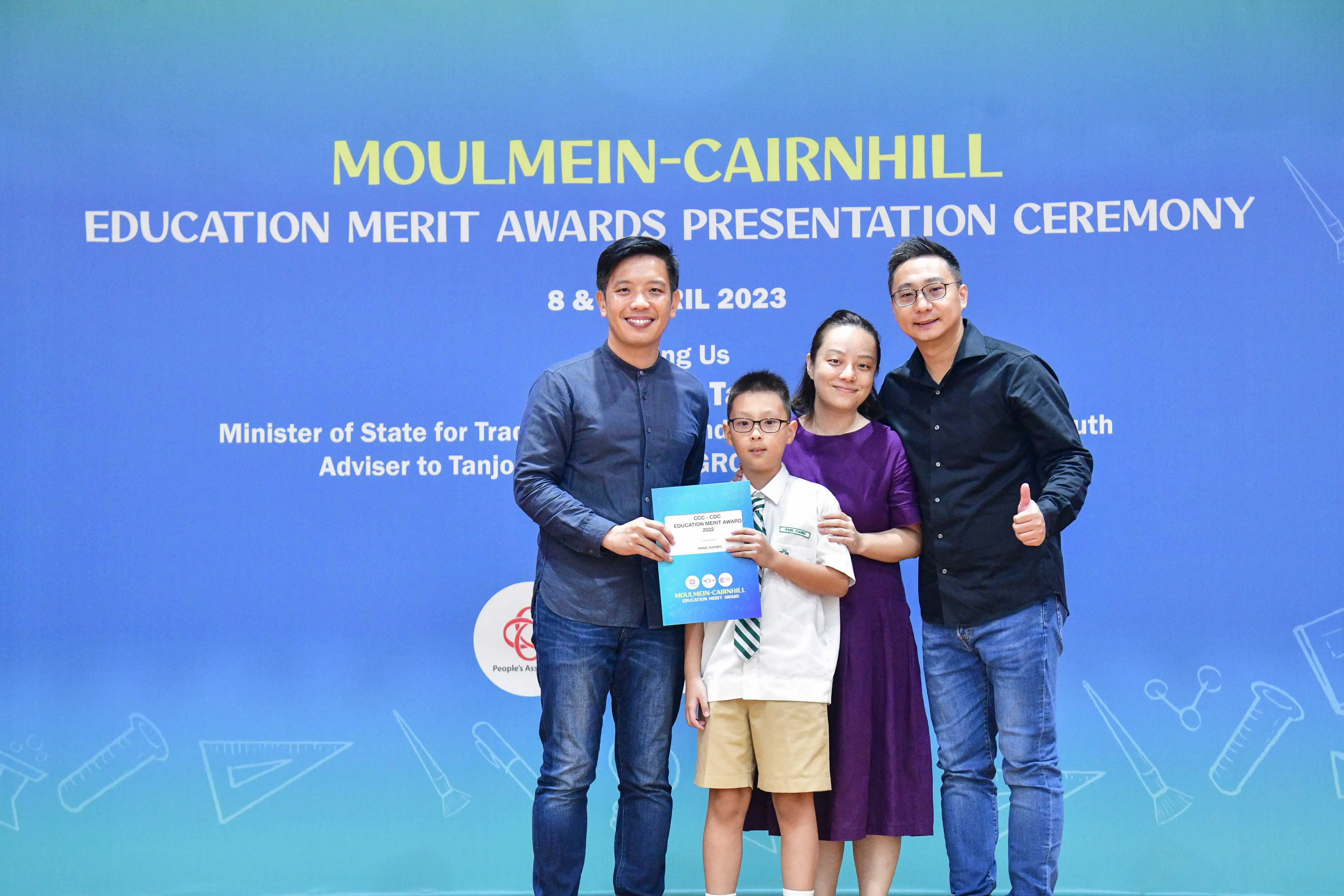 Three adults and a boy holding a certificate pose at the Moulmein-Cairnhill Education Merit Awards Ceremony 2023.