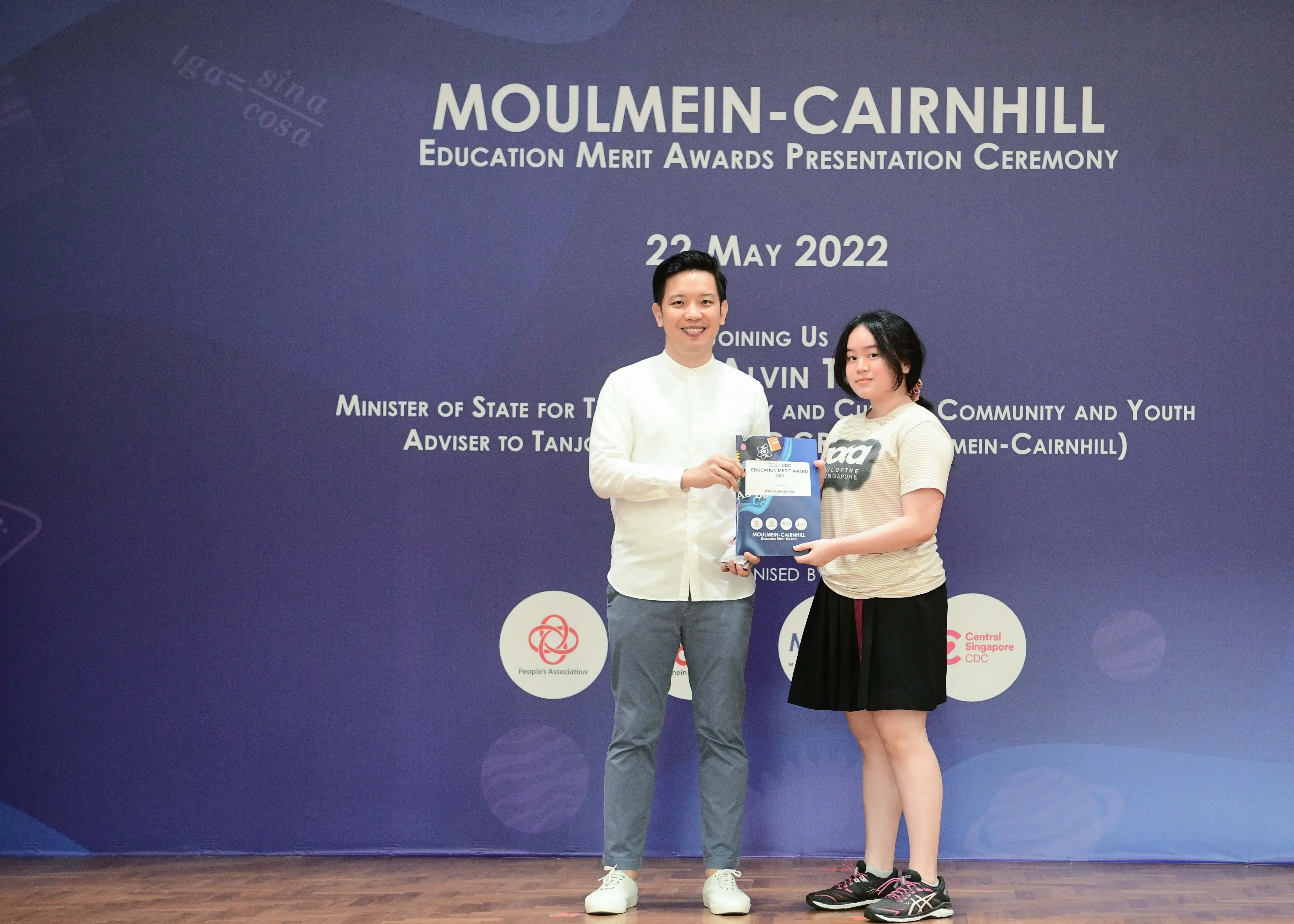 Two people hold an award certificate at the Moulmein-Cairnhill Education Merit Awards Ceremony on 22 May 2022.