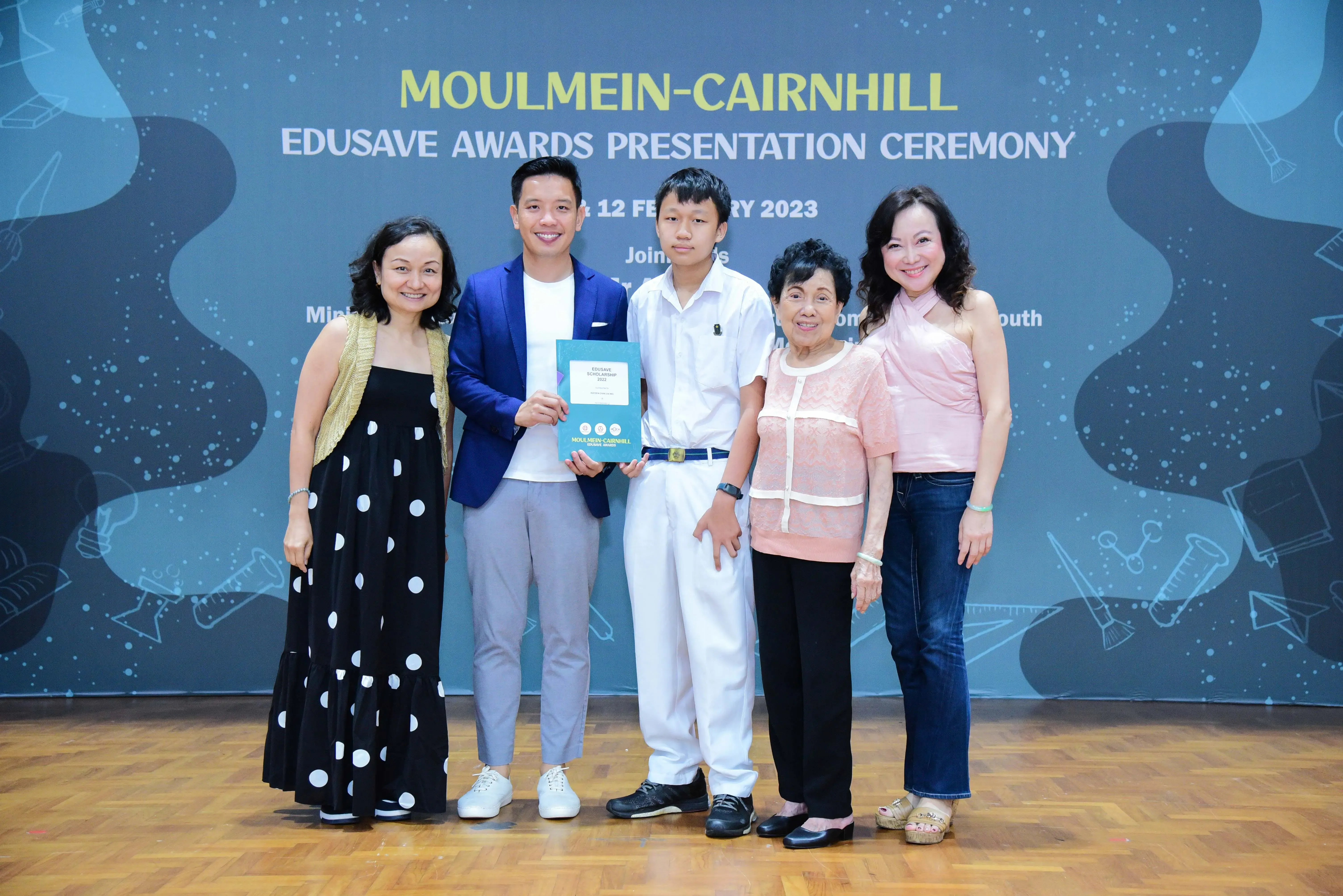 Five people pose smiling at the Moulmein-Cairnhill Edusave Awards Presentation Ceremony on 12 February 2023.