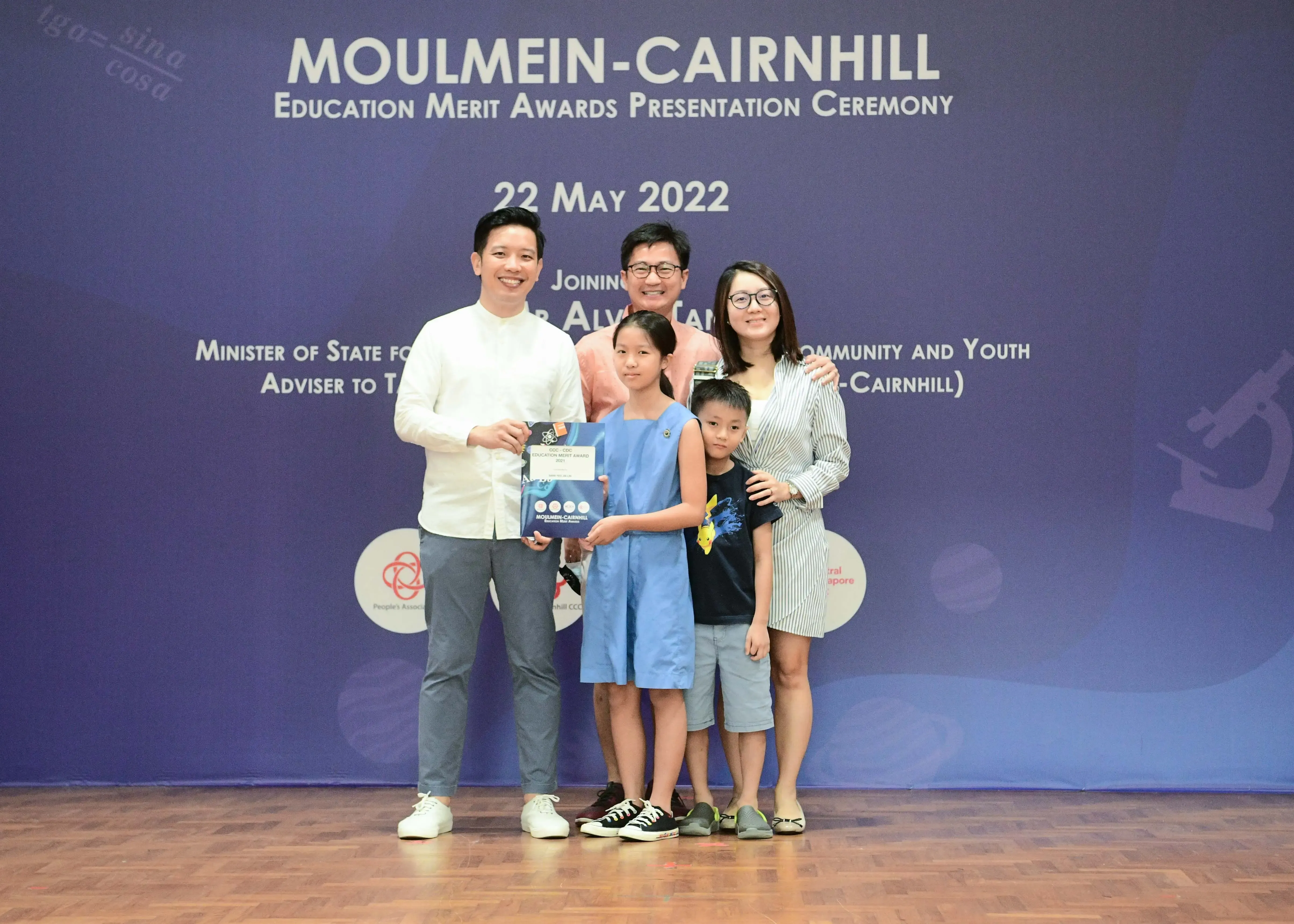 Five people pose with an award certificate at the Moulmein-Cairnhill Education Merit Awards Ceremony on 22 May 2022.