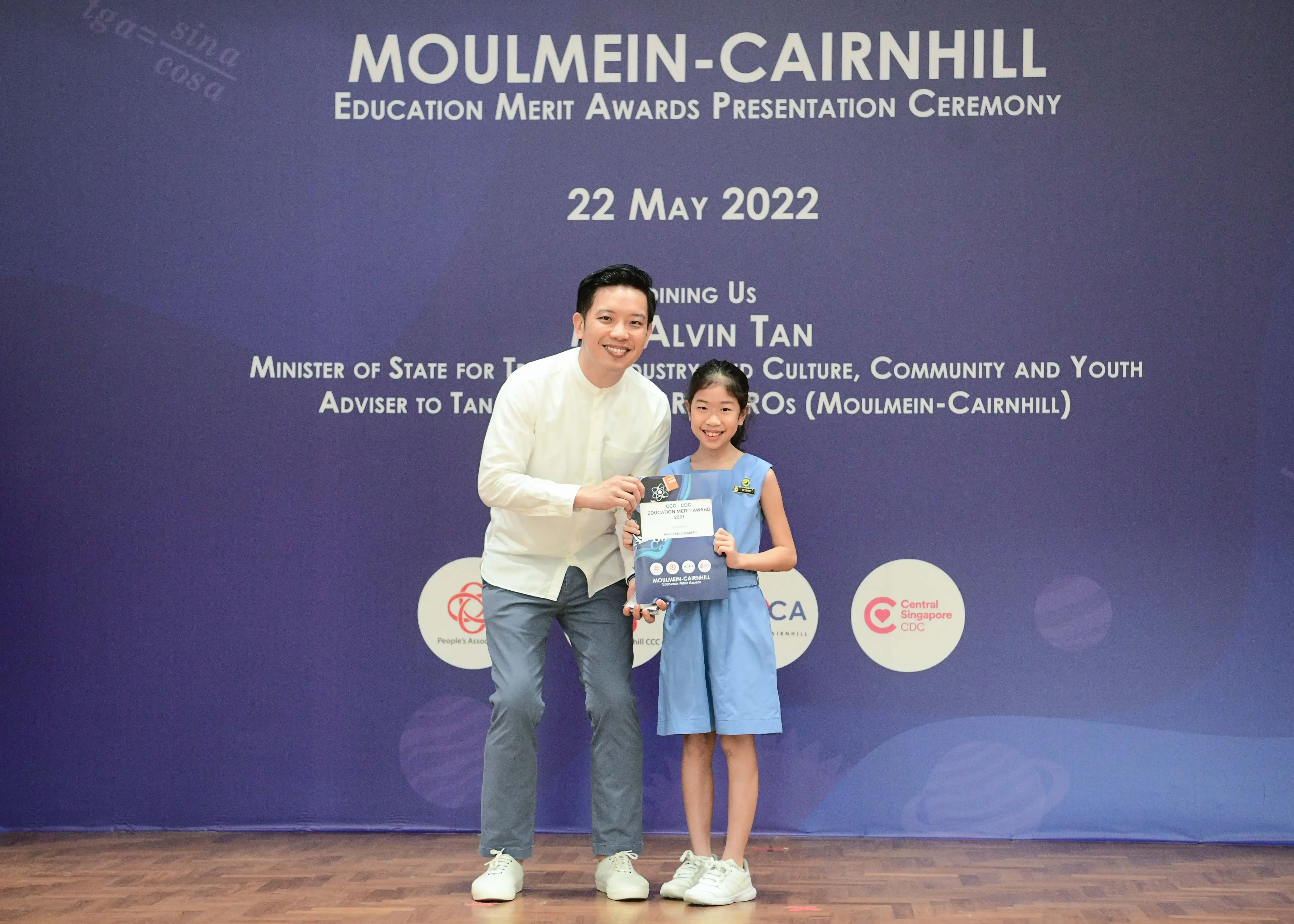 A man and a young girl pose together holding an award at the Moulmein-Cairnhill Education Merit Awards on 22 May 2022.