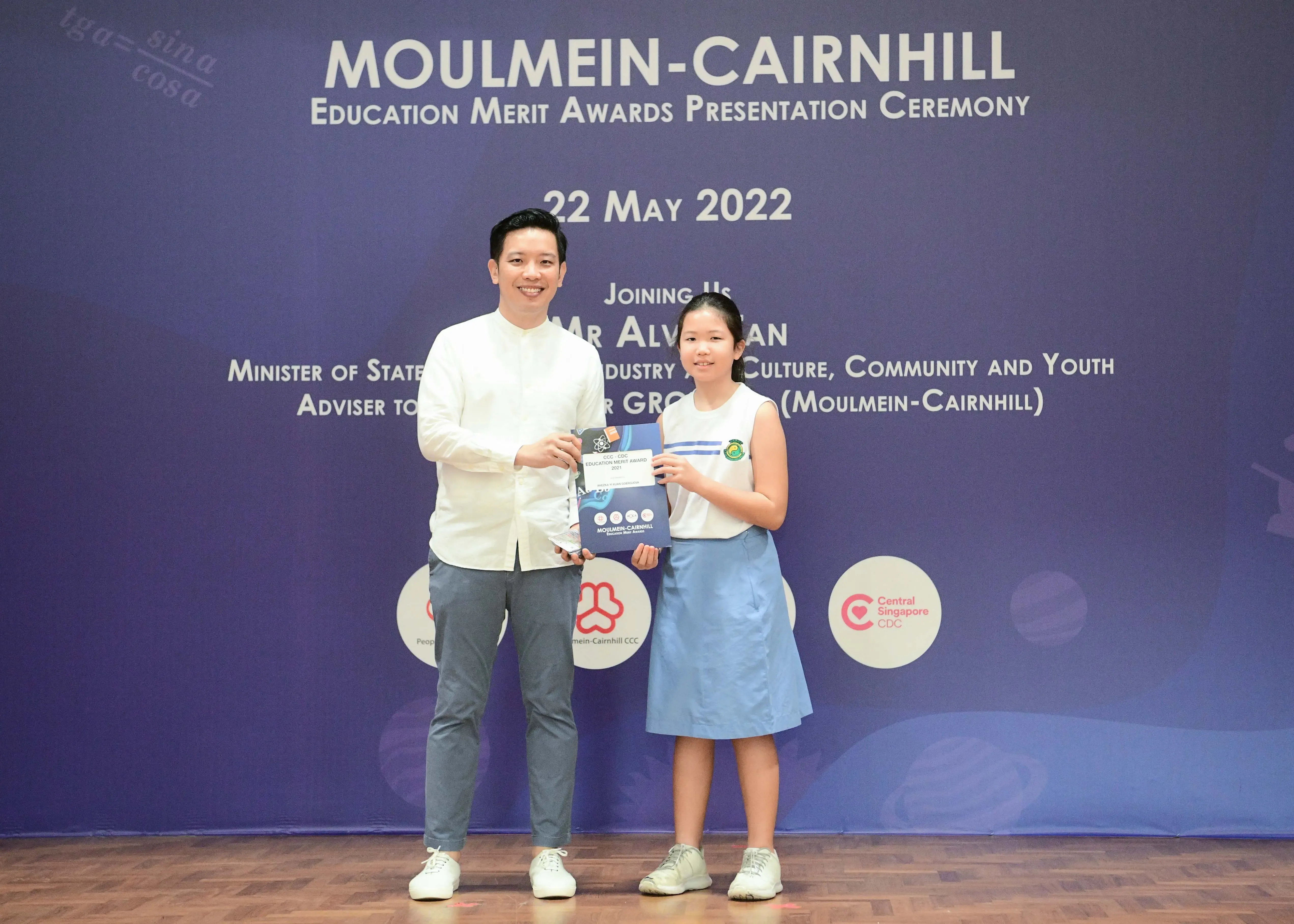 A man and a young girl hold an award booklet at the Moulmein-Cairnhill Education Merit Awards on 22 May 2022.