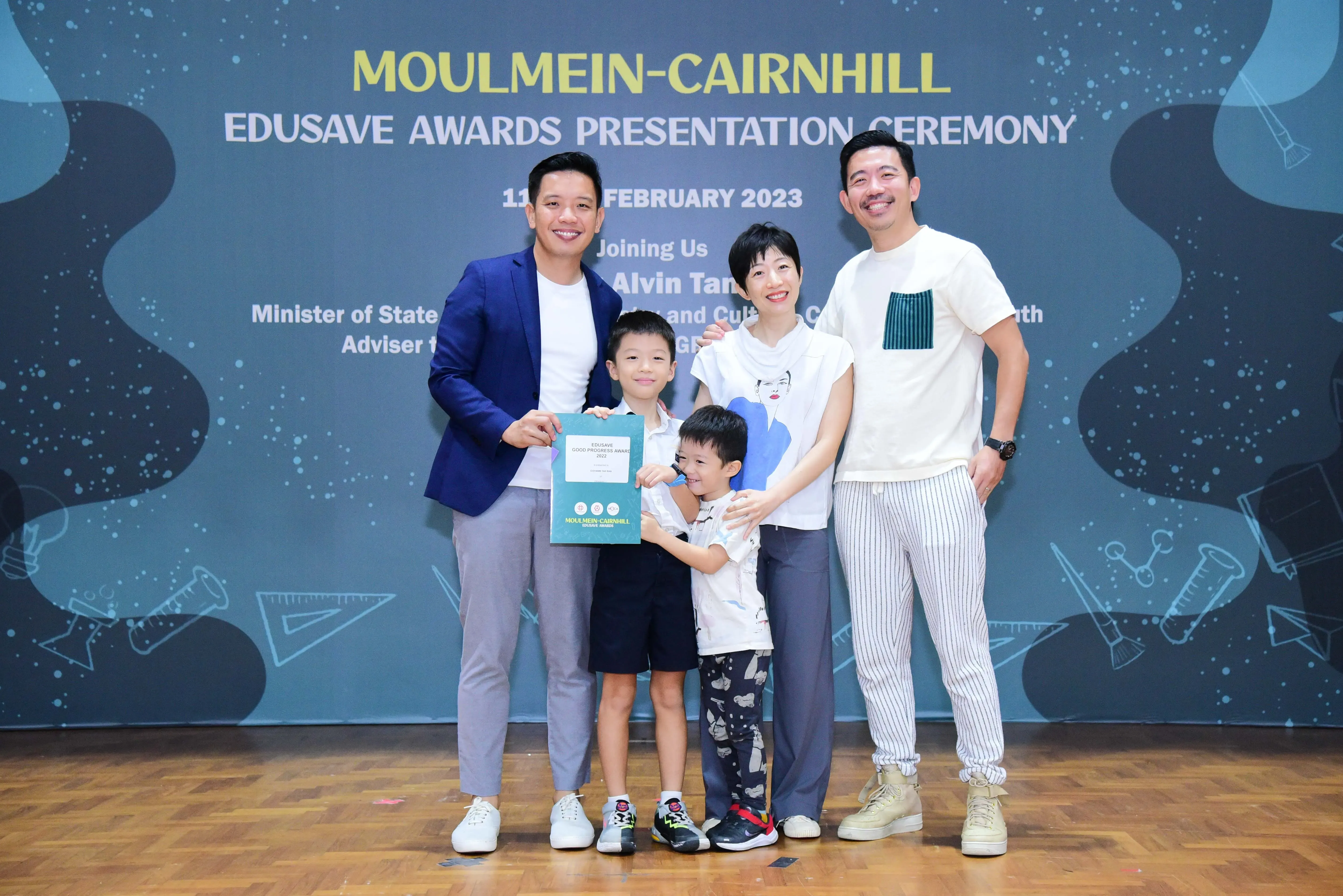Four adults and two children pose at the Moulmein-Cairnhill Edusave Awards Presentation Ceremony, February 2023.