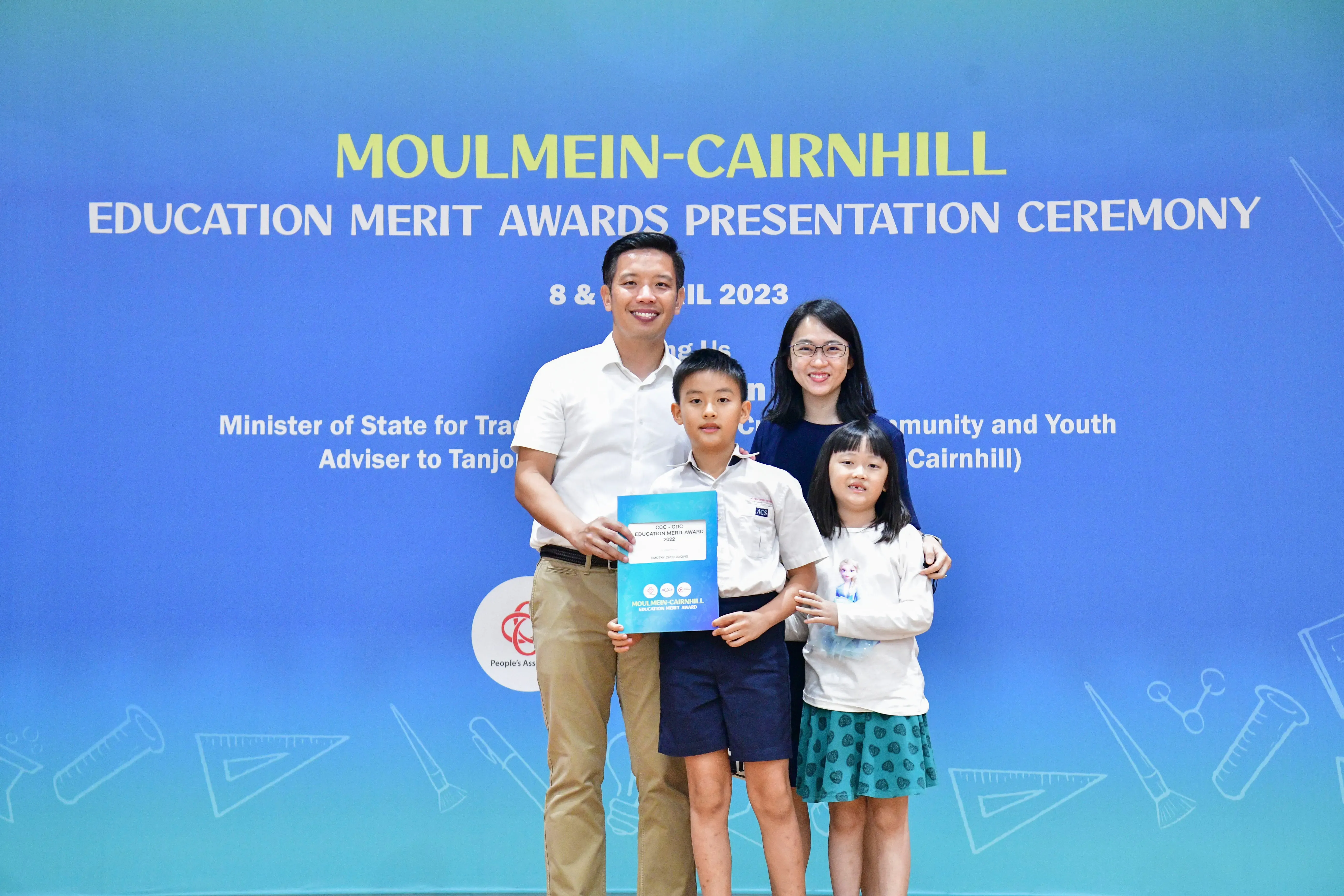 Family of four posing with an award certificate at the Moulmein-Cairnhill Education Merit Awards Ceremony 2023.