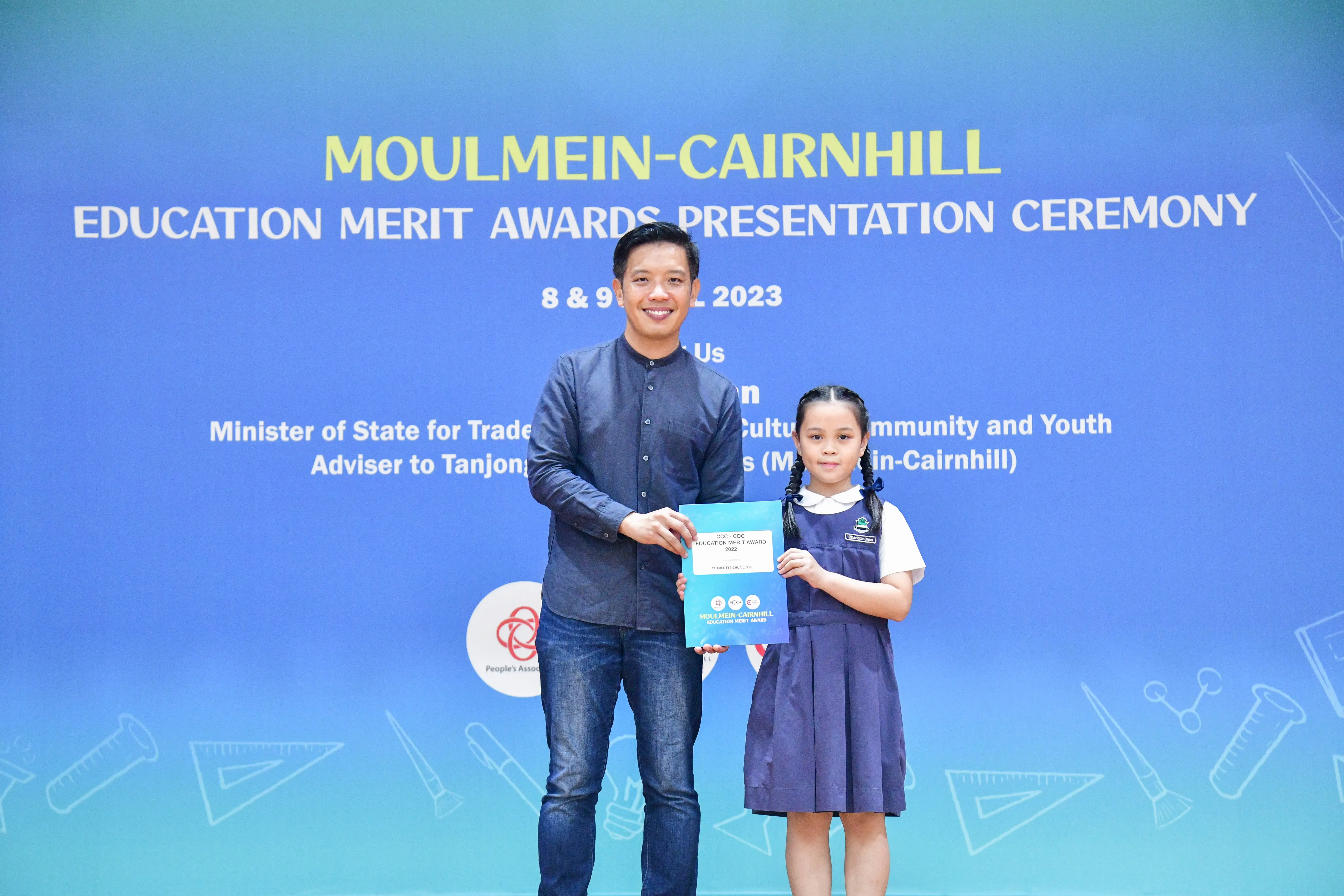A man and a young girl in school uniform hold a certificate at the Moulmein-Cairnhill Education Merit Awards 2023.