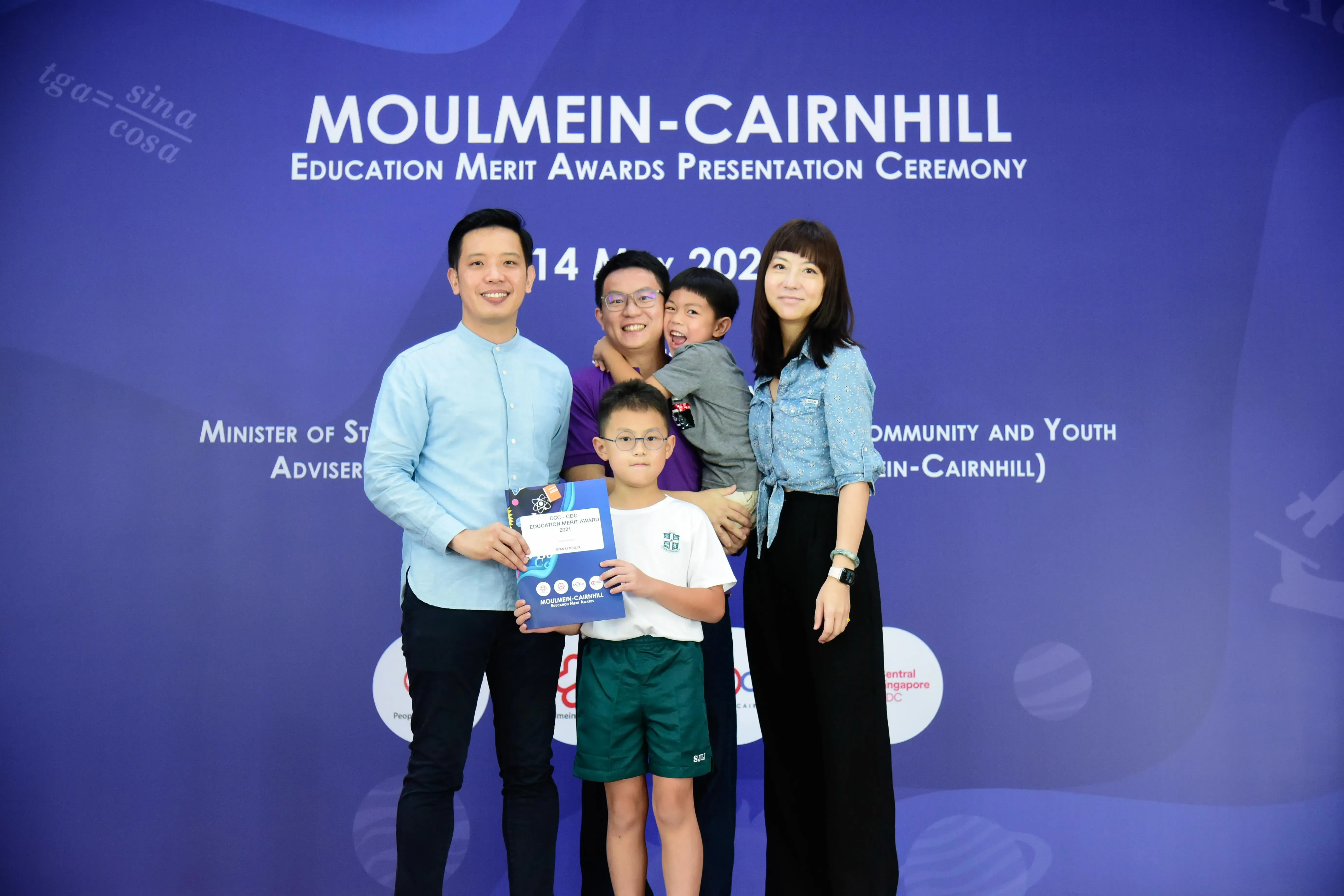 Family of five posing with an award certificate at the Moulmein-Cairnhill Education Merit Awards Presentation Ceremony.