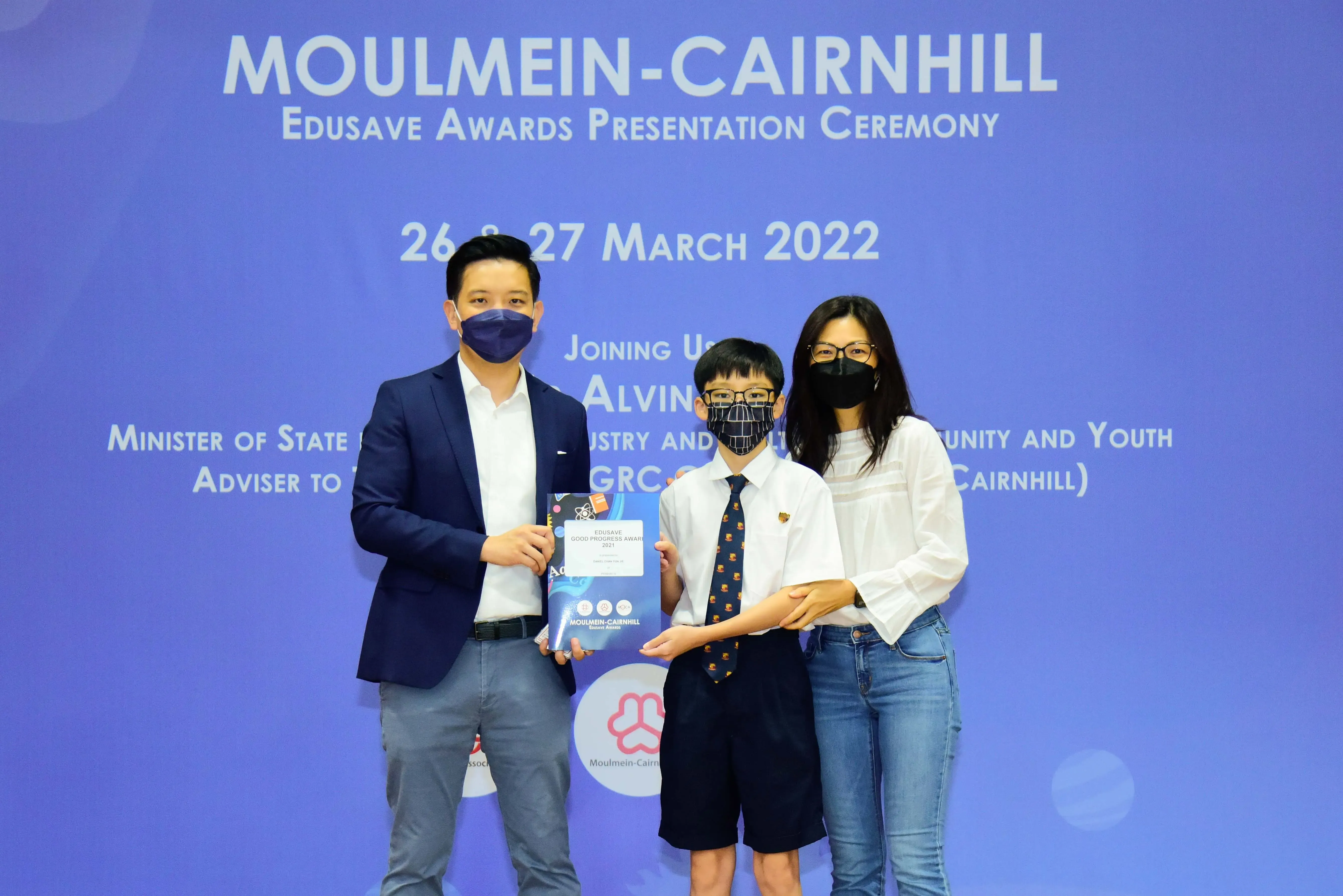 Three masked people pose at the Moulmein-Cairnhill Edusave Awards Presentation Ceremony, March 2022.