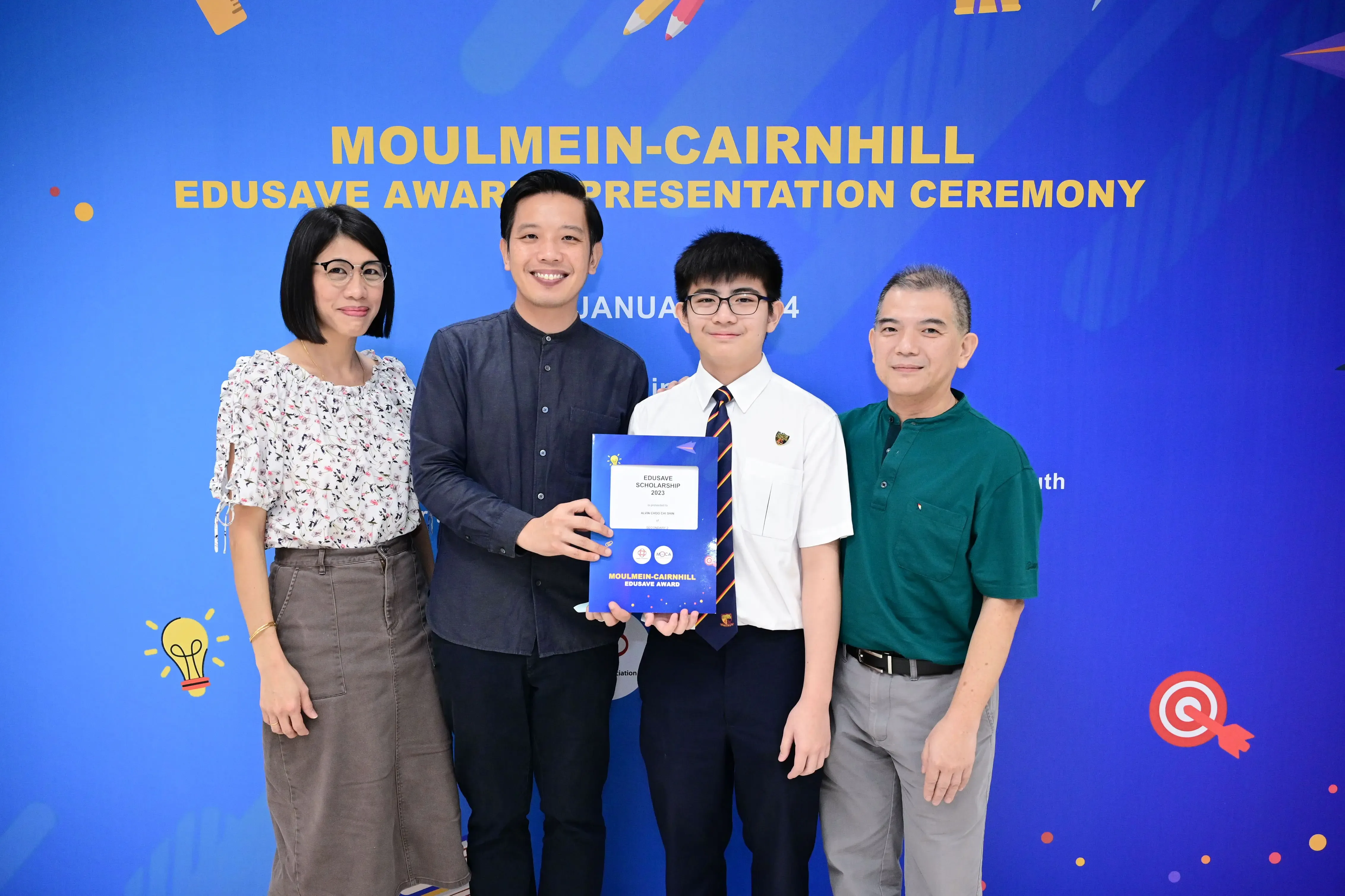 Four people pose together at the Moulmein-Cairnhill Edusave Award Presentation Ceremony, holding a scholarship certificate.