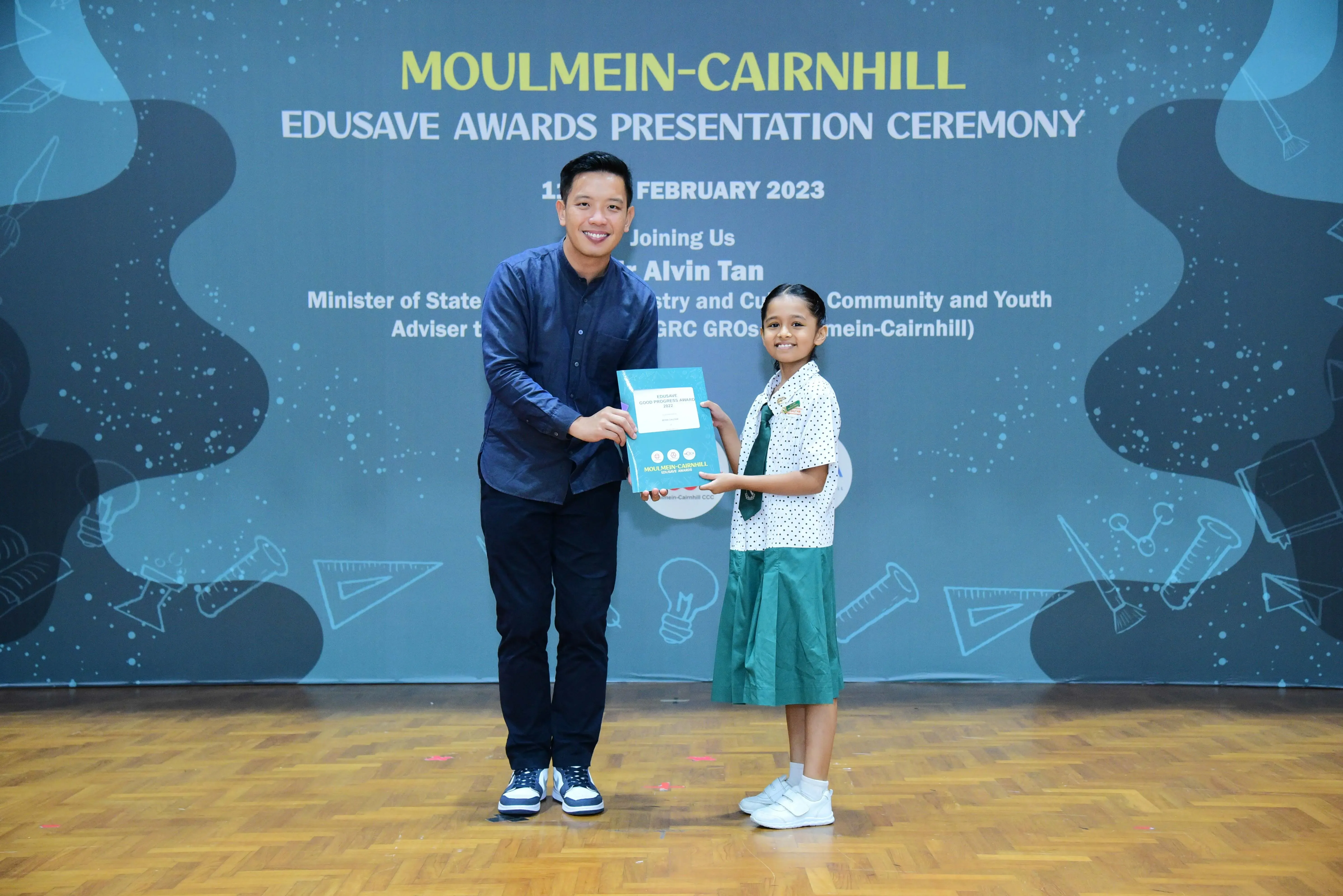 Man and young girl holding an award booklet at Moulmein-Cairnhill Edusave Awards Ceremony, February 2023.