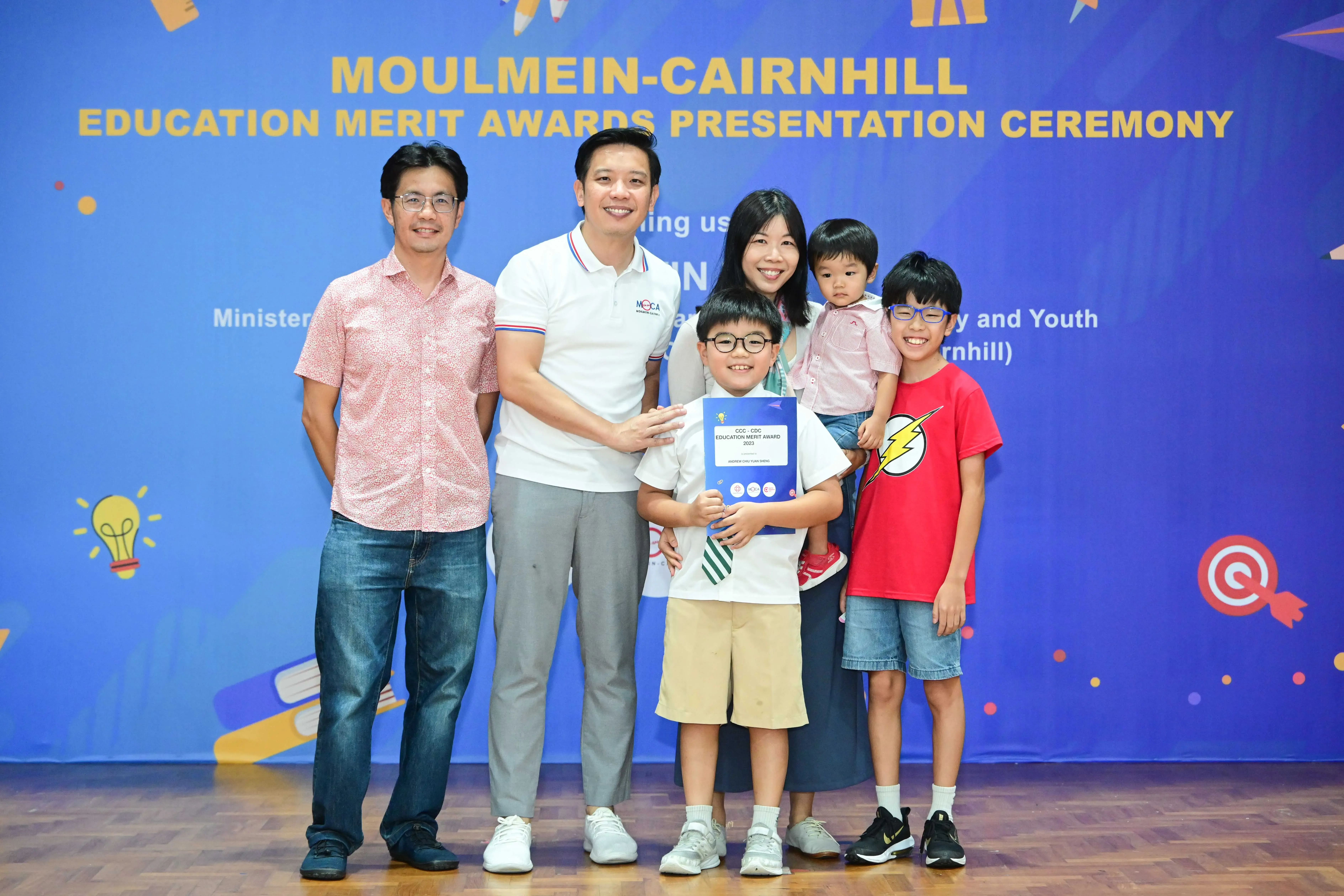 A family poses with a boy holding a certificate at the Moulmein-Cairnhill Education Merit Awards Presentation Ceremony.
