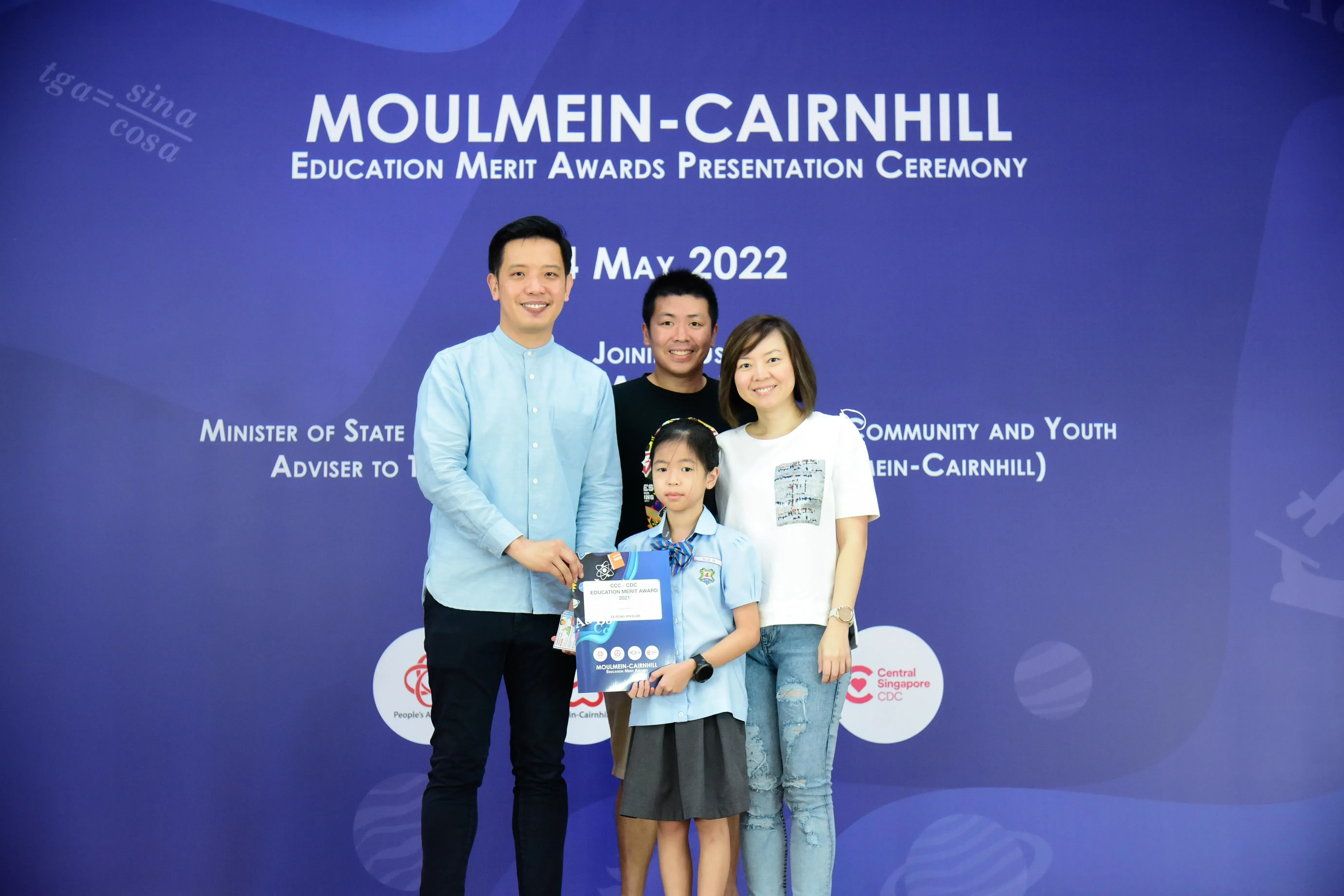 Three adults and a young girl pose with an award at the Moulmein-Cairnhill Education Merit Awards ceremony, May 2022.