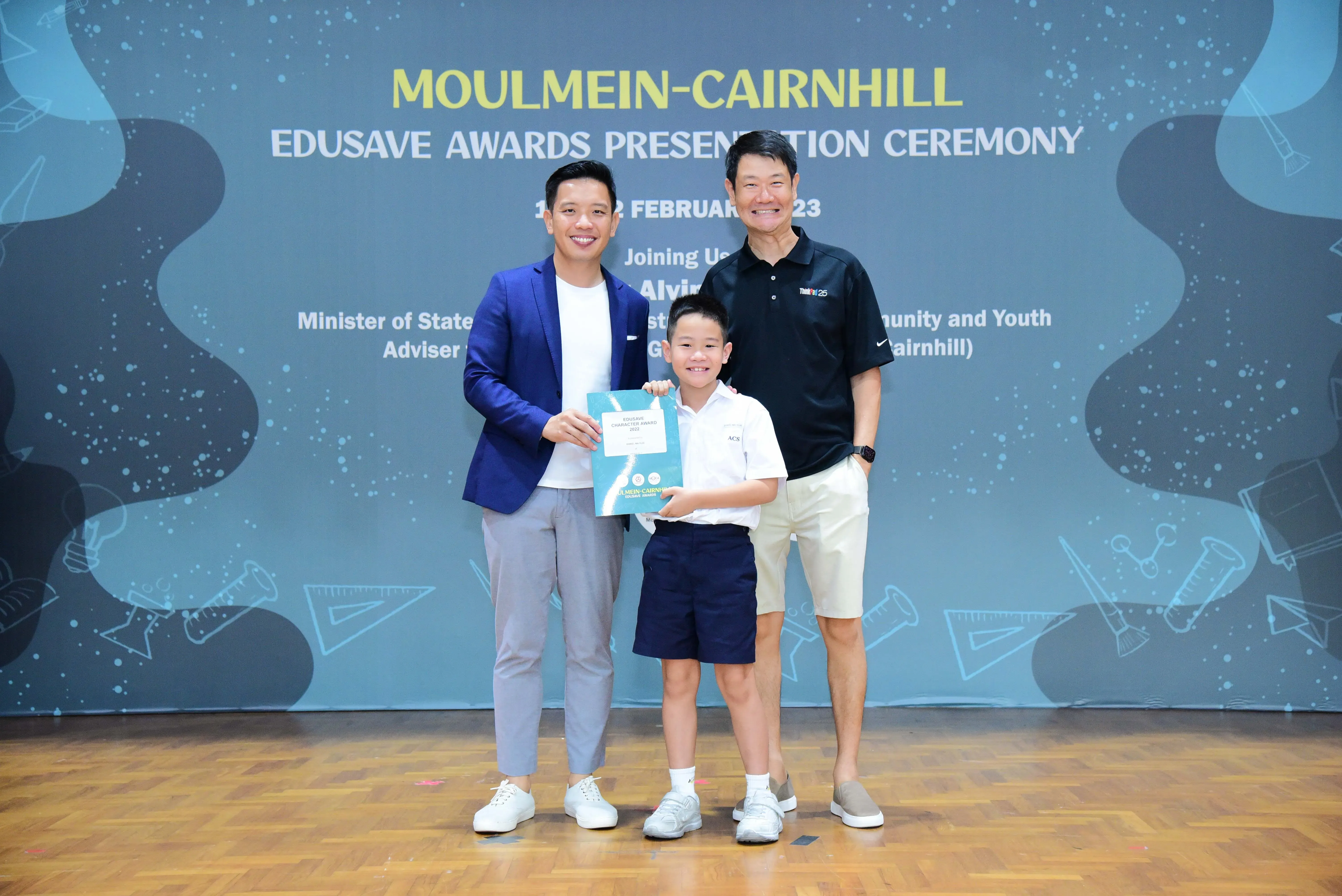 Two men and a young boy holding a certificate pose at the Moulmein-Cairnhill Edusave Awards Presentation Ceremony.