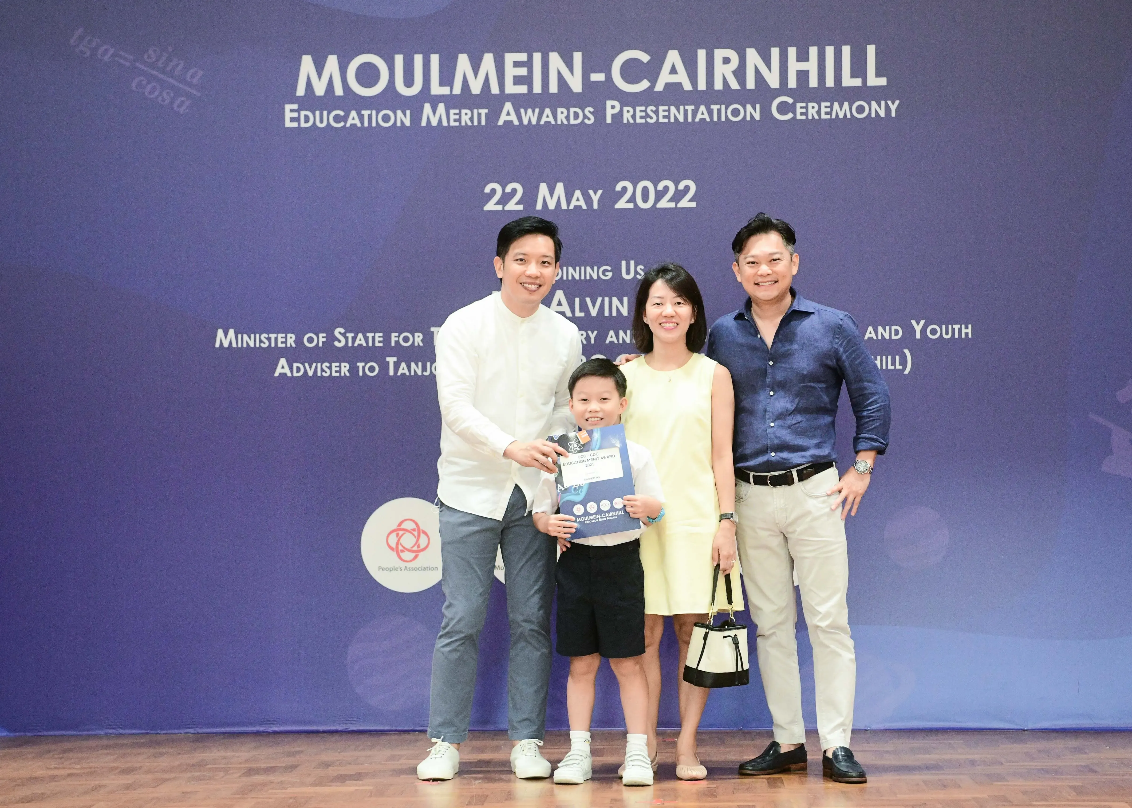 Three adults and a young boy pose smiling at the Moulmein-Cairnhill Education Merit Awards Ceremony on 22 May 2022.
