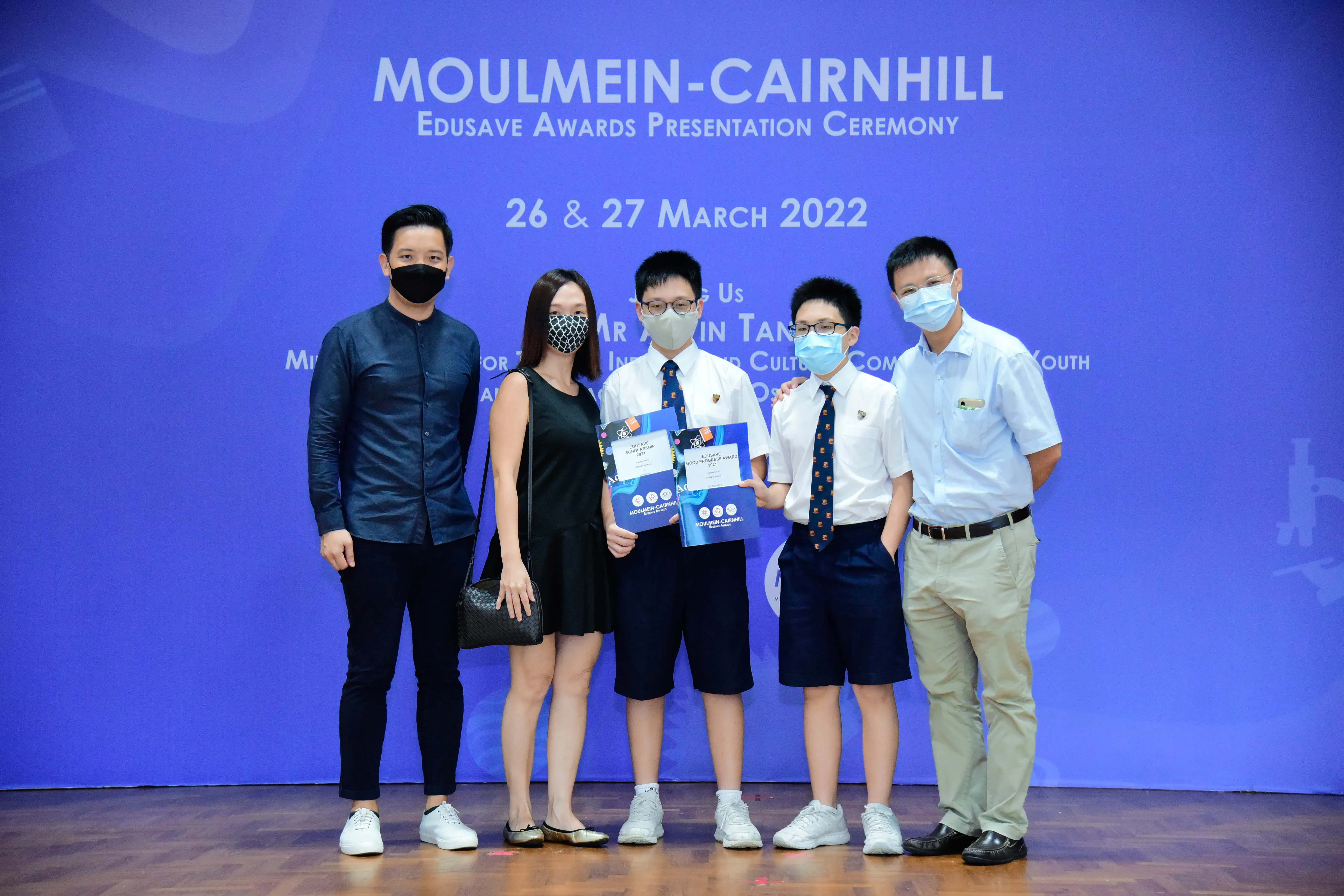 Five masked people pose at the Moulmein-Cairnhill Edusave Awards Presentation Ceremony on 26-27 March 2022.