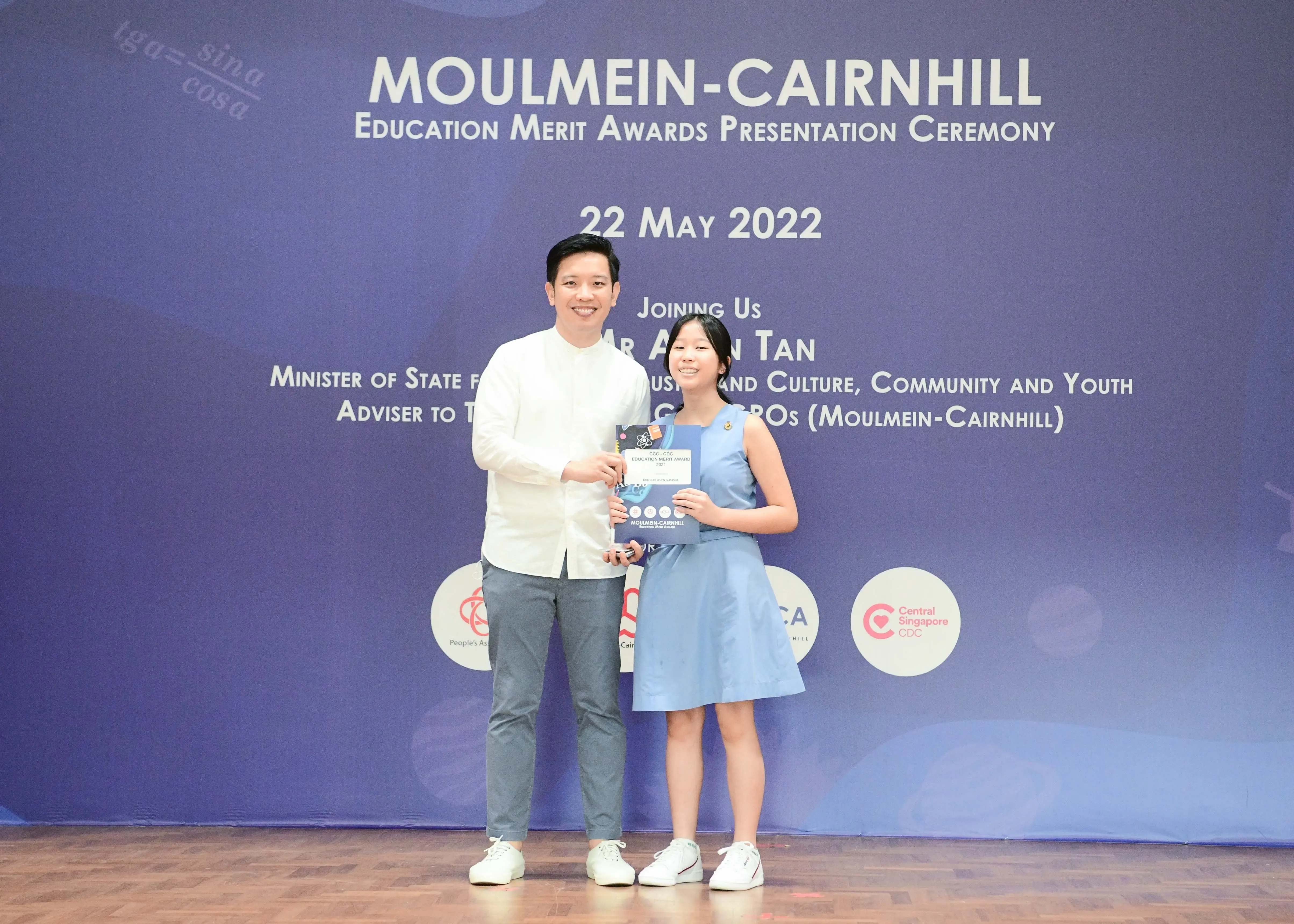 A man and a girl pose holding an award at the Moulmein-Cairnhill Education Merit Awards Ceremony on 22 May 2022.