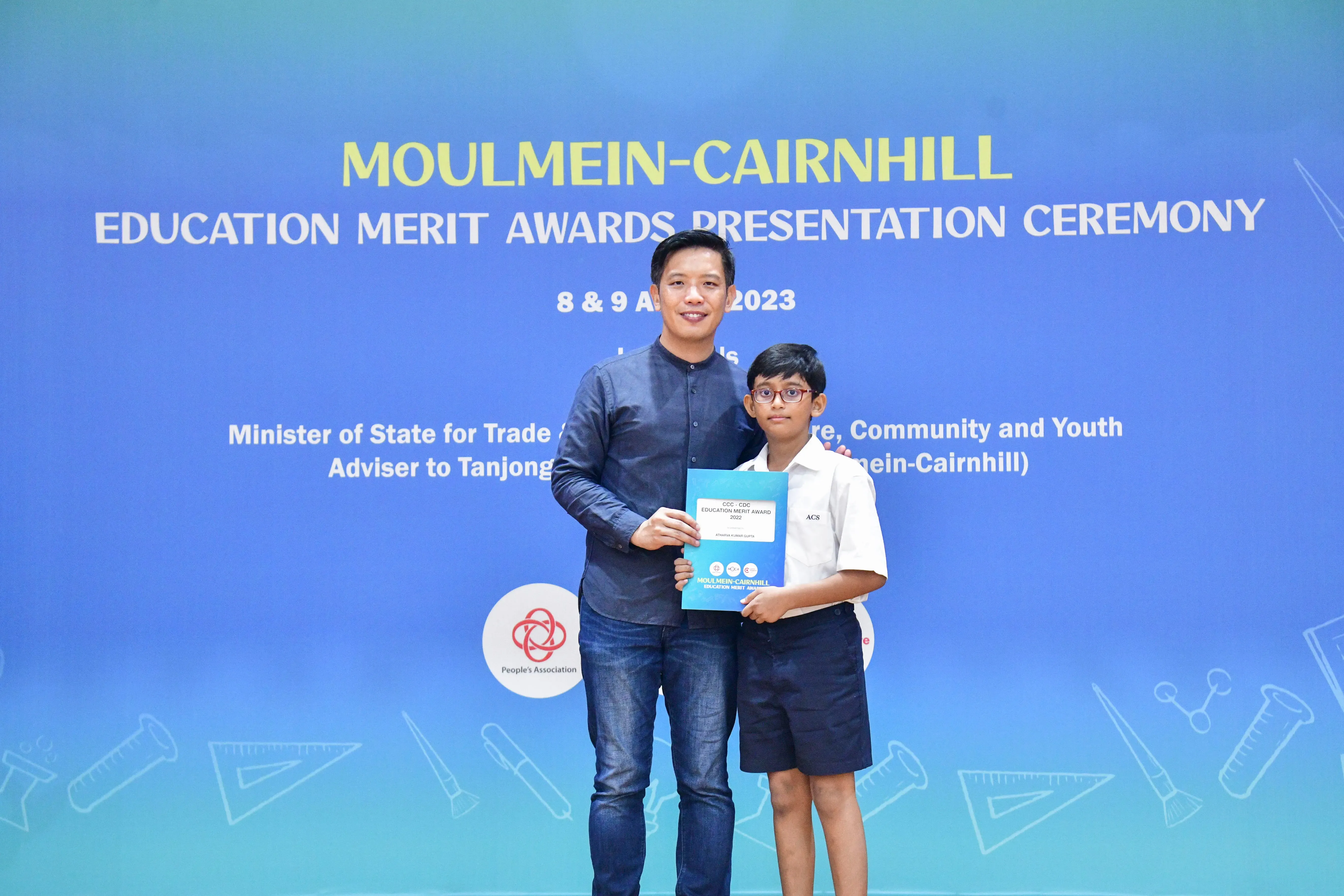 An adult and a young student hold an award certificate at the Moulmein-Cairnhill Education Merit Awards 2023.