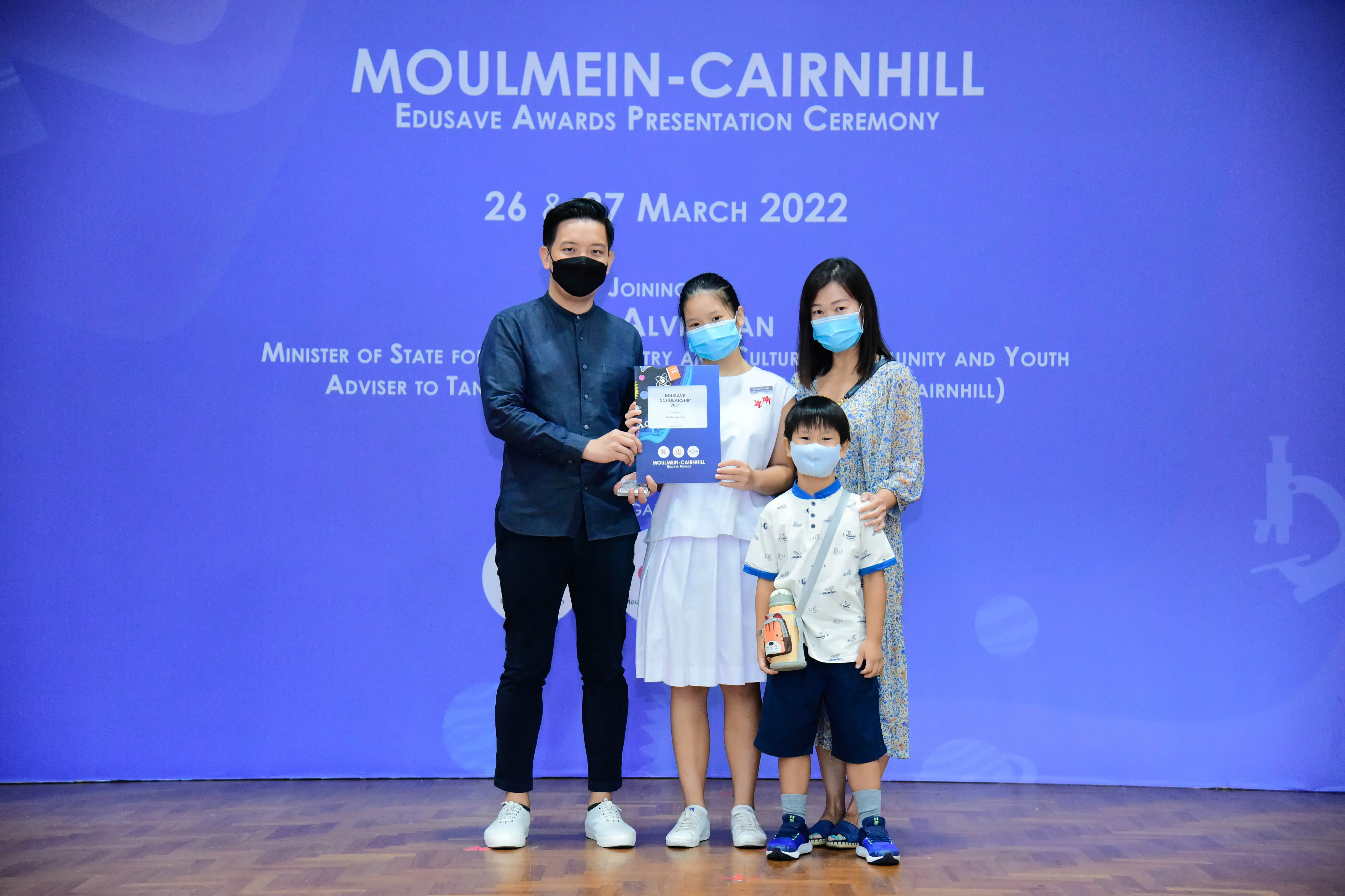 Four masked people pose at the Moulmein-Cairnhill Edusave Awards Presentation Ceremony in March 2022.