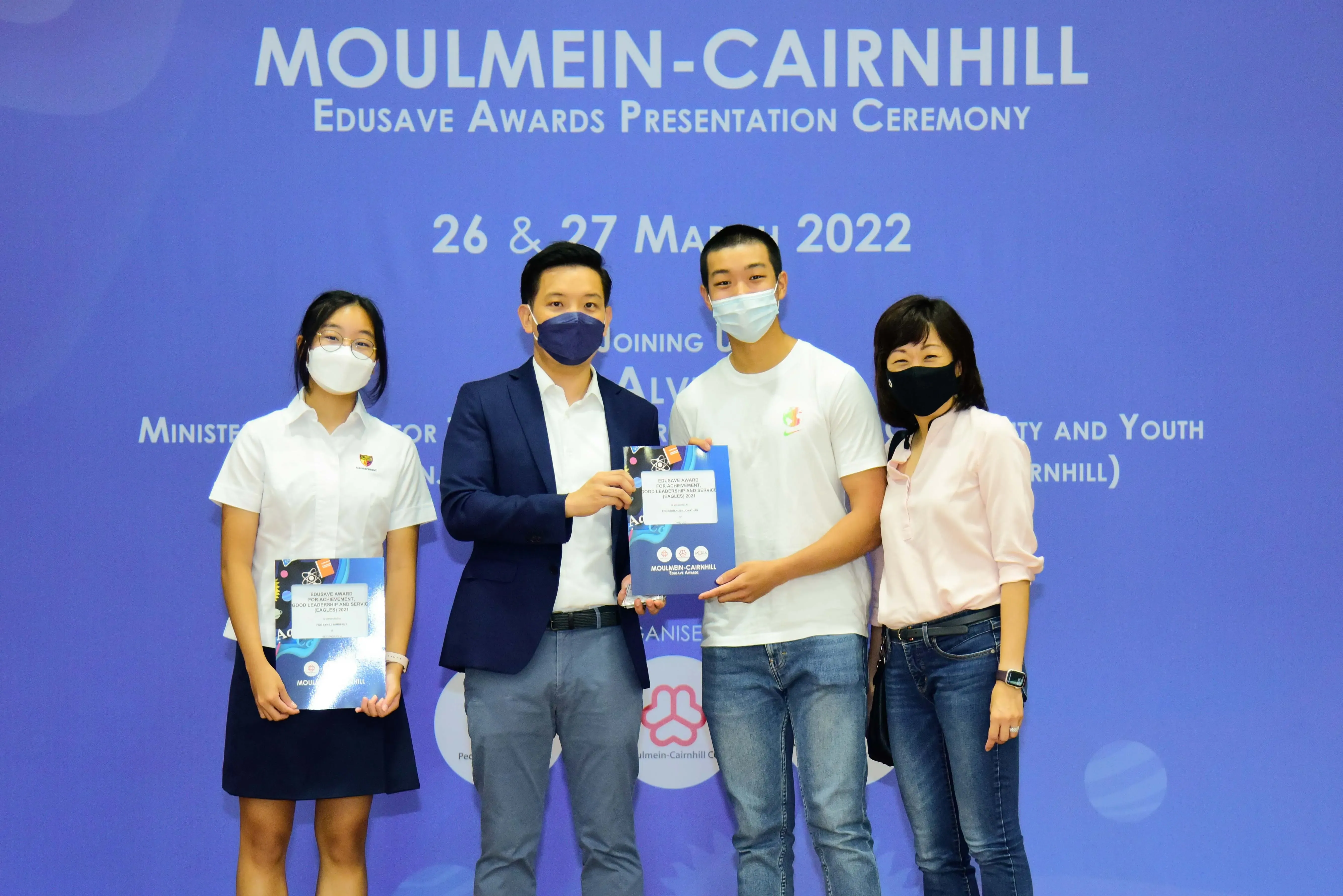 Four masked people pose at the Moulmein-Cairnhill Edusave Awards Presentation Ceremony on 26-27 March 2022.