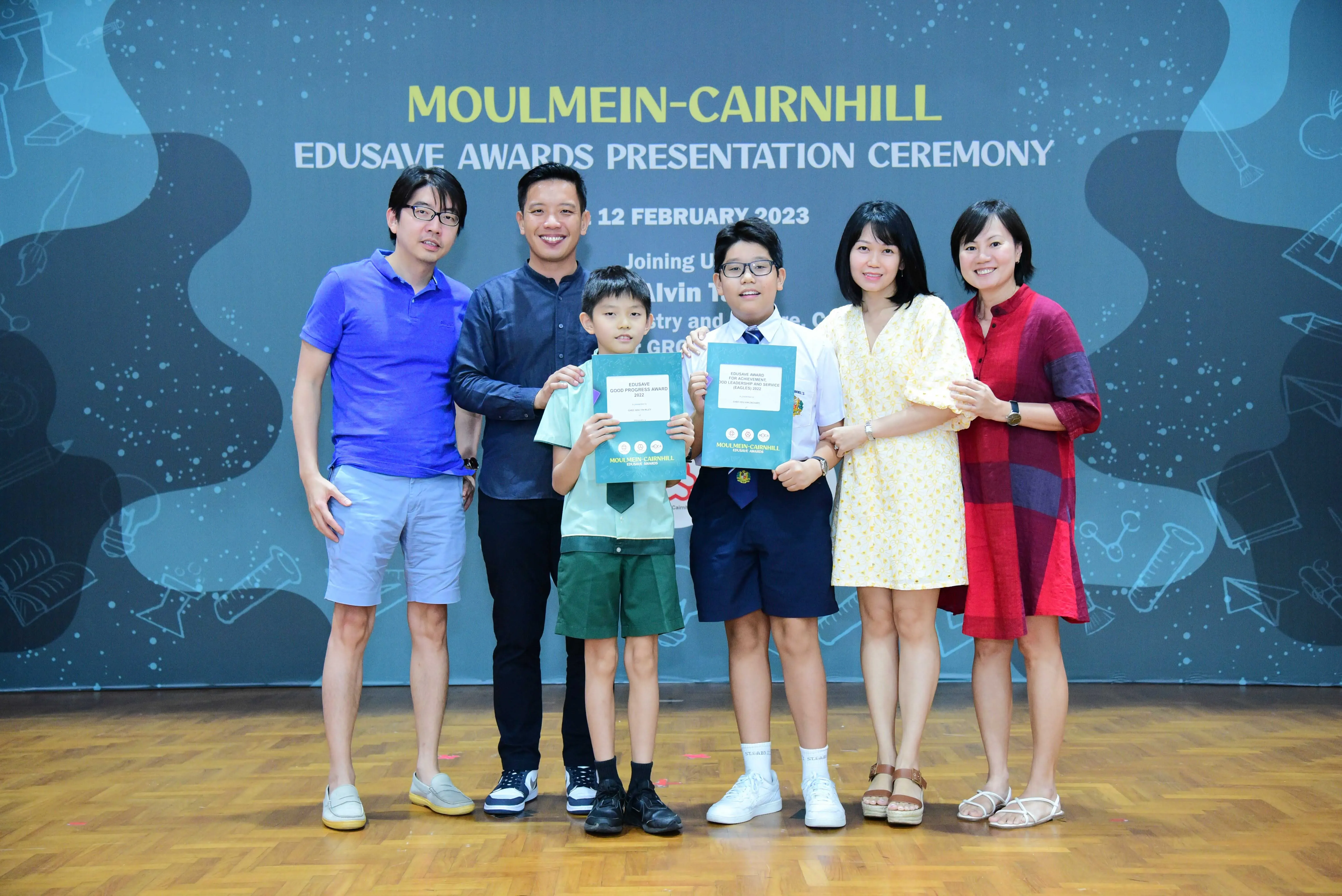 Six people pose at the Moulmein-Cairnhill Edusave Awards Presentation Ceremony on 12 February 2023, two children holding certificates.