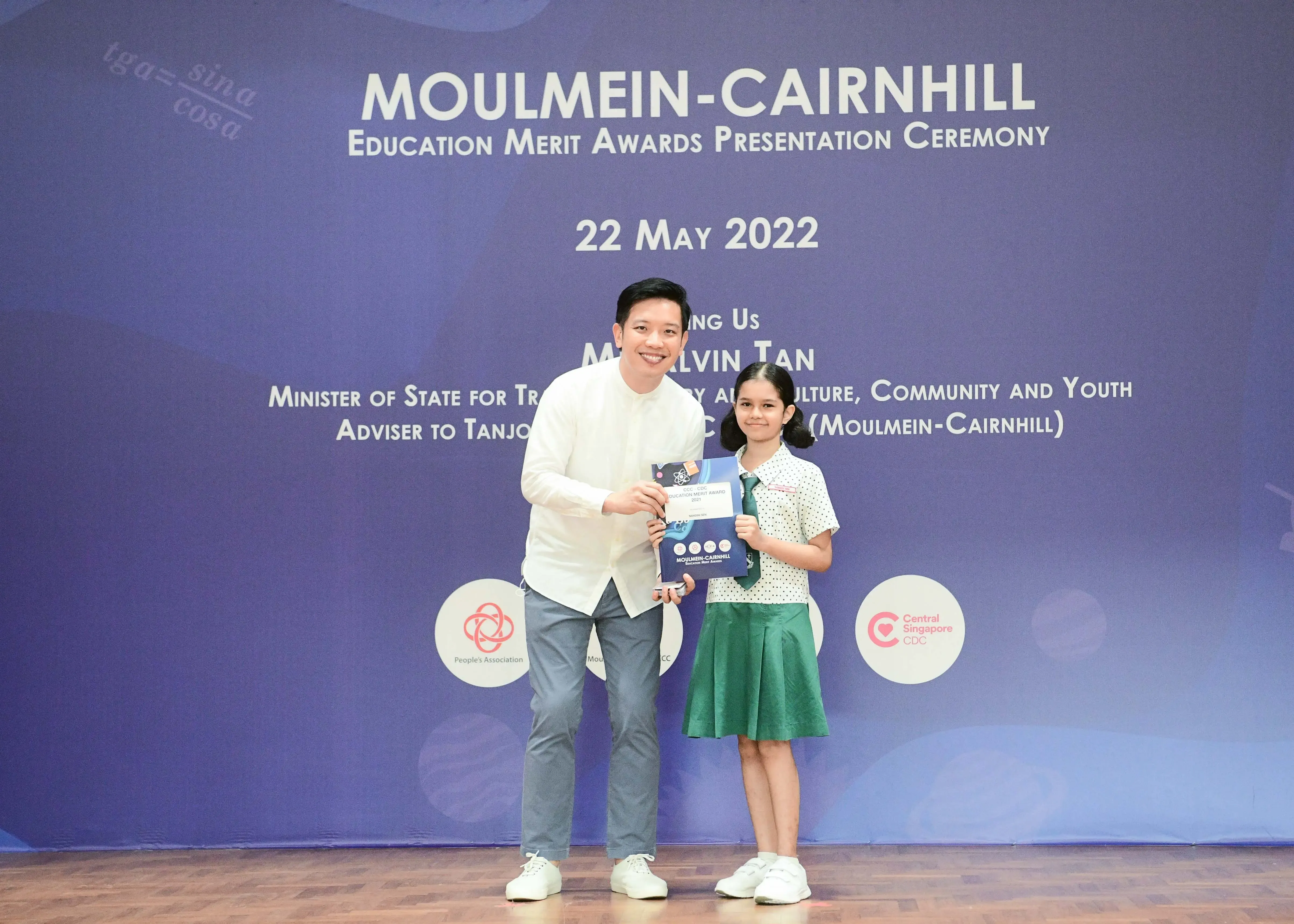 A man and a young girl hold an award certificate at the Moulmein-Cairnhill Education Merit Awards on 22 May 2022.