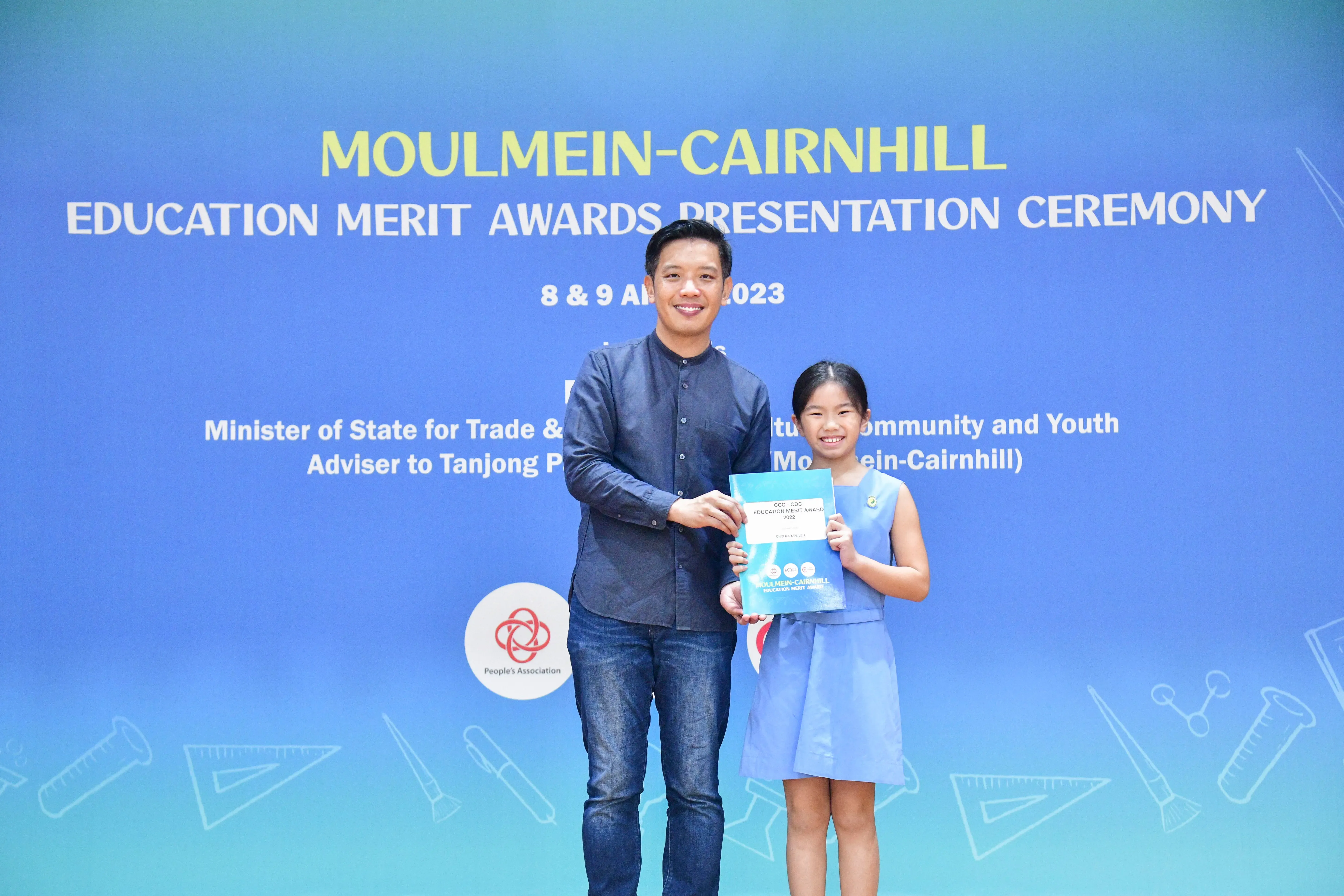 A man and a young girl hold a certificate together at the Moulmein-Cairnhill Education Merit Awards 2023.