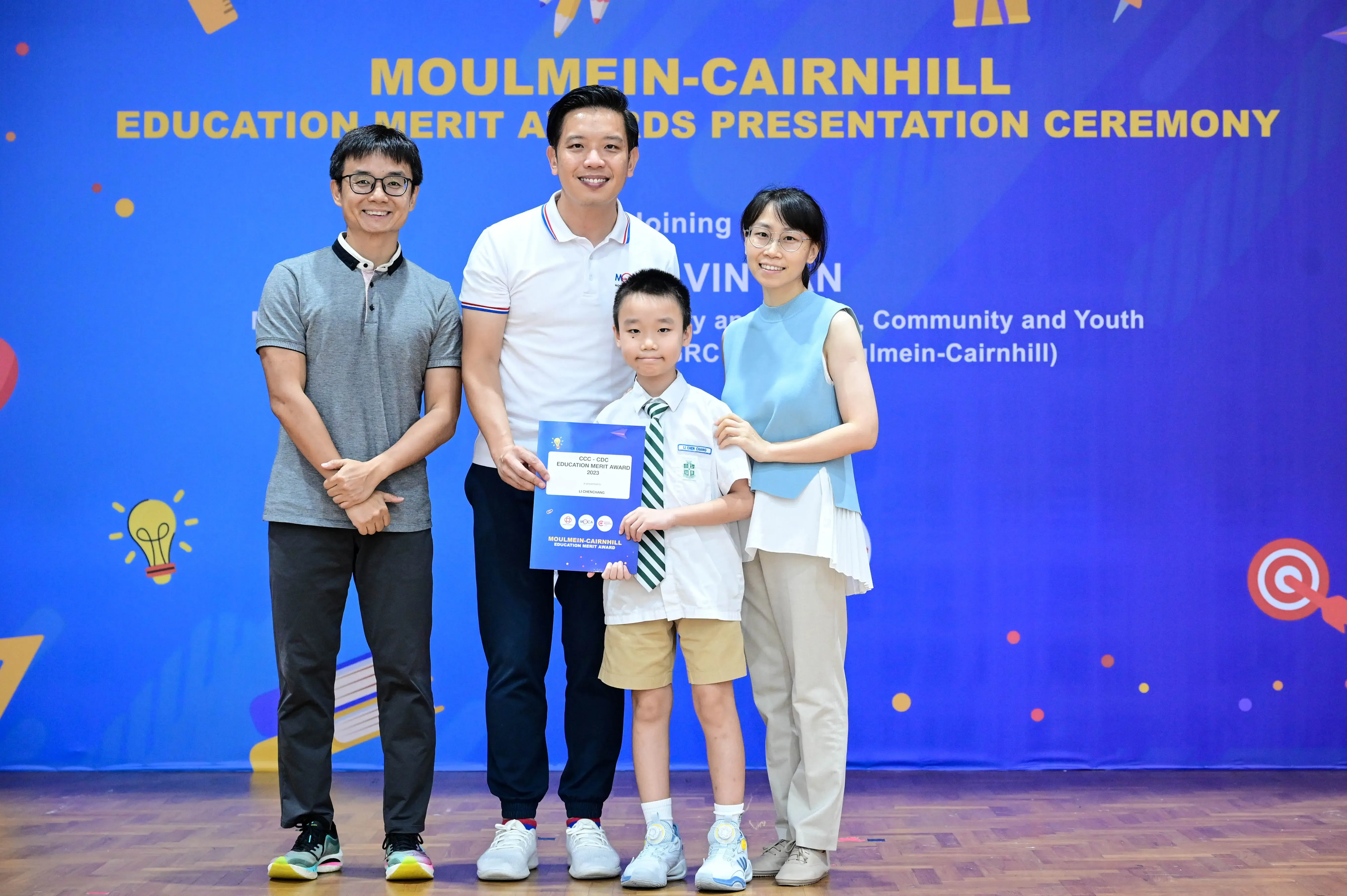 Three adults and a boy holding a certificate pose at the Moulmein-Cairnhill Education Merit Awards Presentation Ceremony.