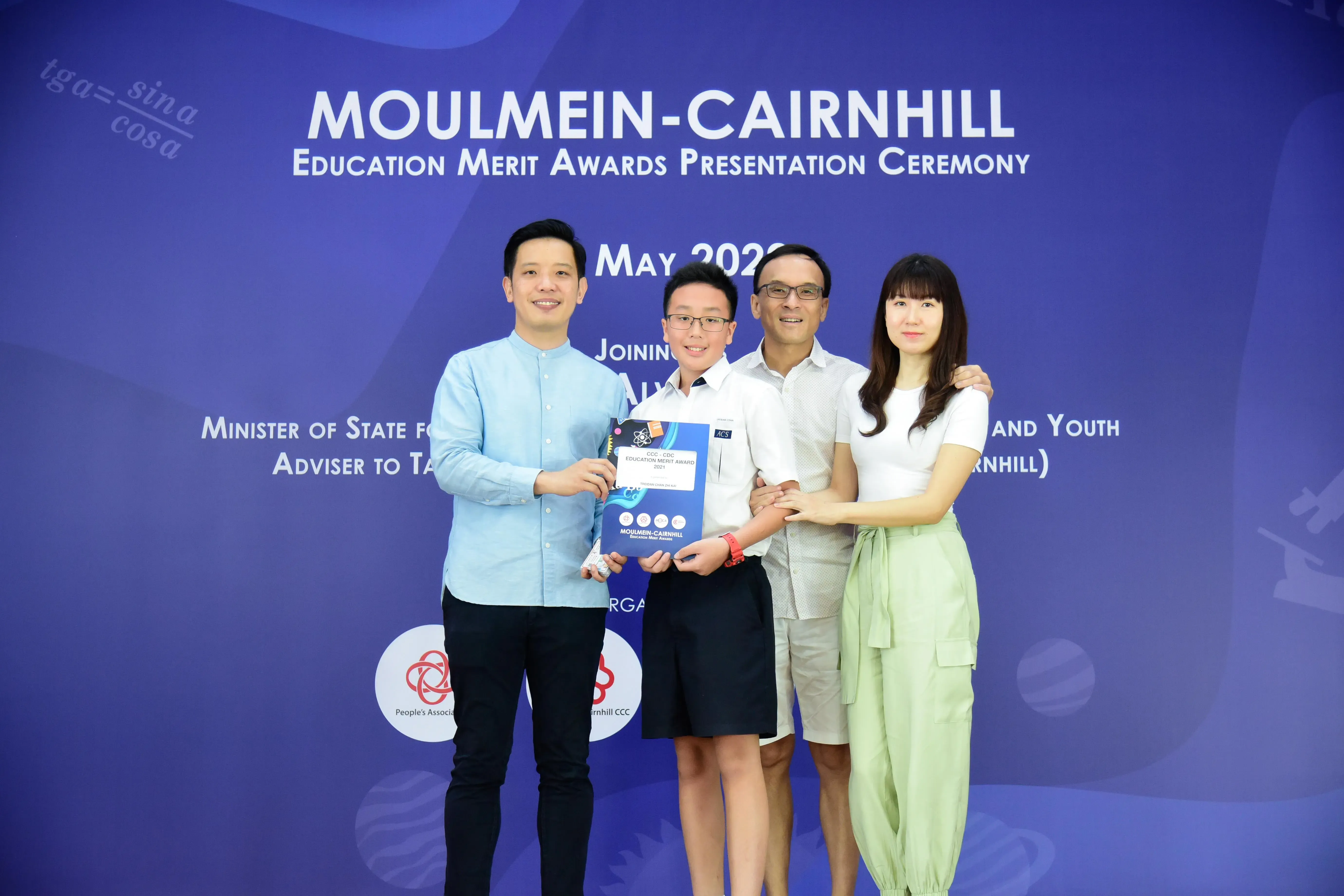 Four people pose together holding an award certificate at the Moulmein-Cairnhill Education Merit Awards Presentation Ceremony.