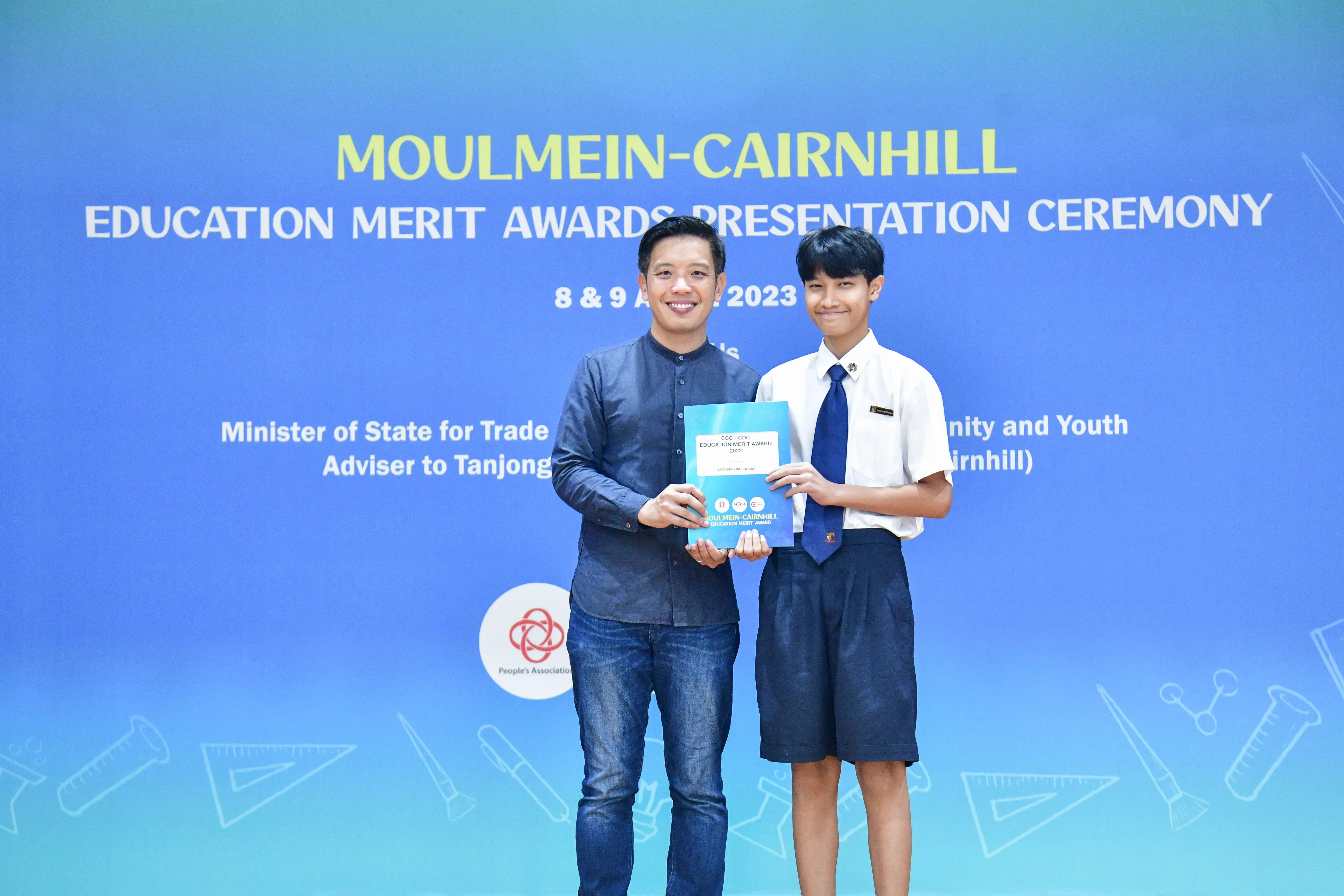 Two people pose holding an award booklet at the Moulmein-Cairnhill Education Merit Awards Ceremony 2023.
