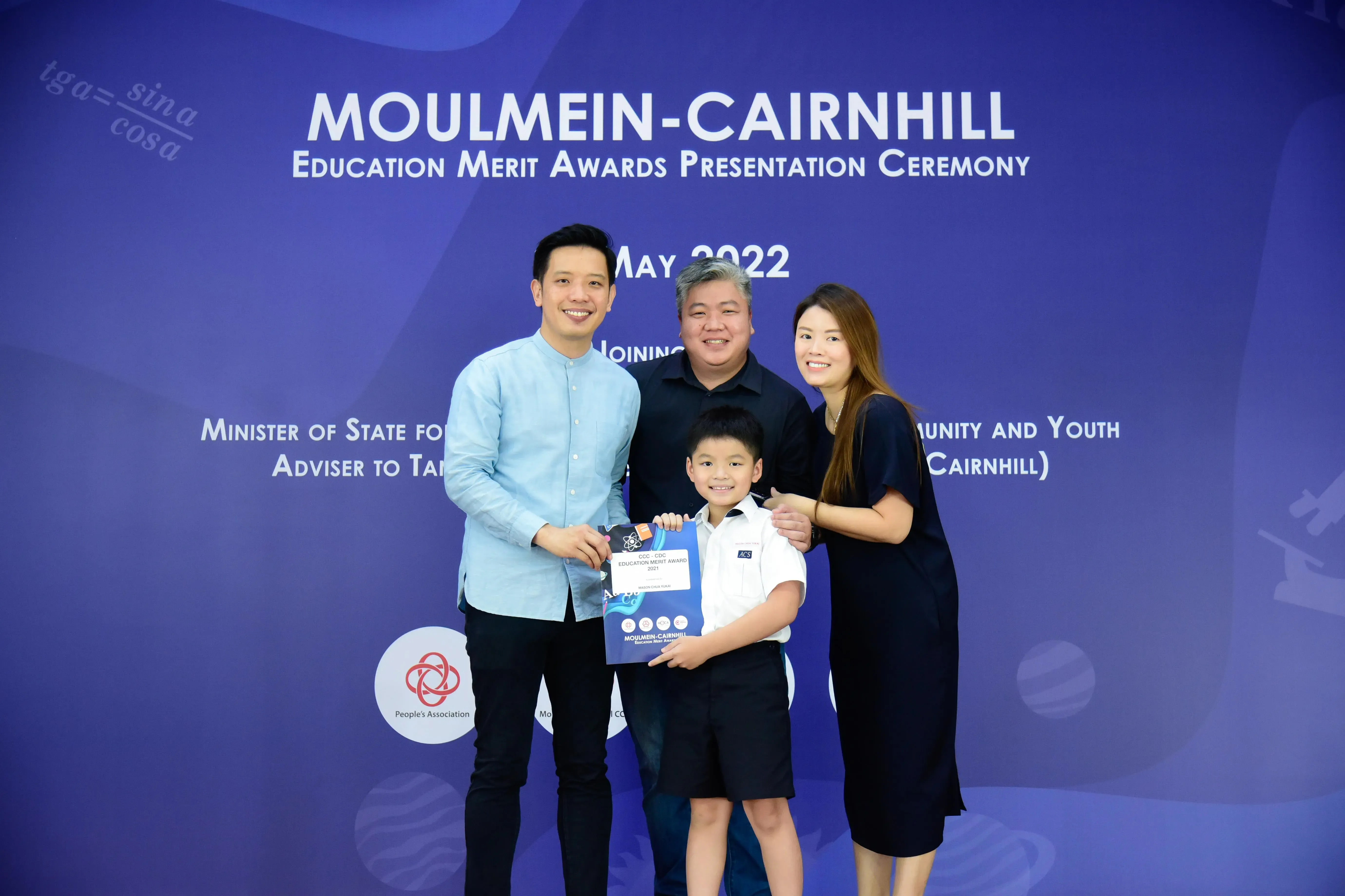 Three adults and a young boy holding an award certificate at the Moulmein-Cairnhill Education Merit Awards May 2022.