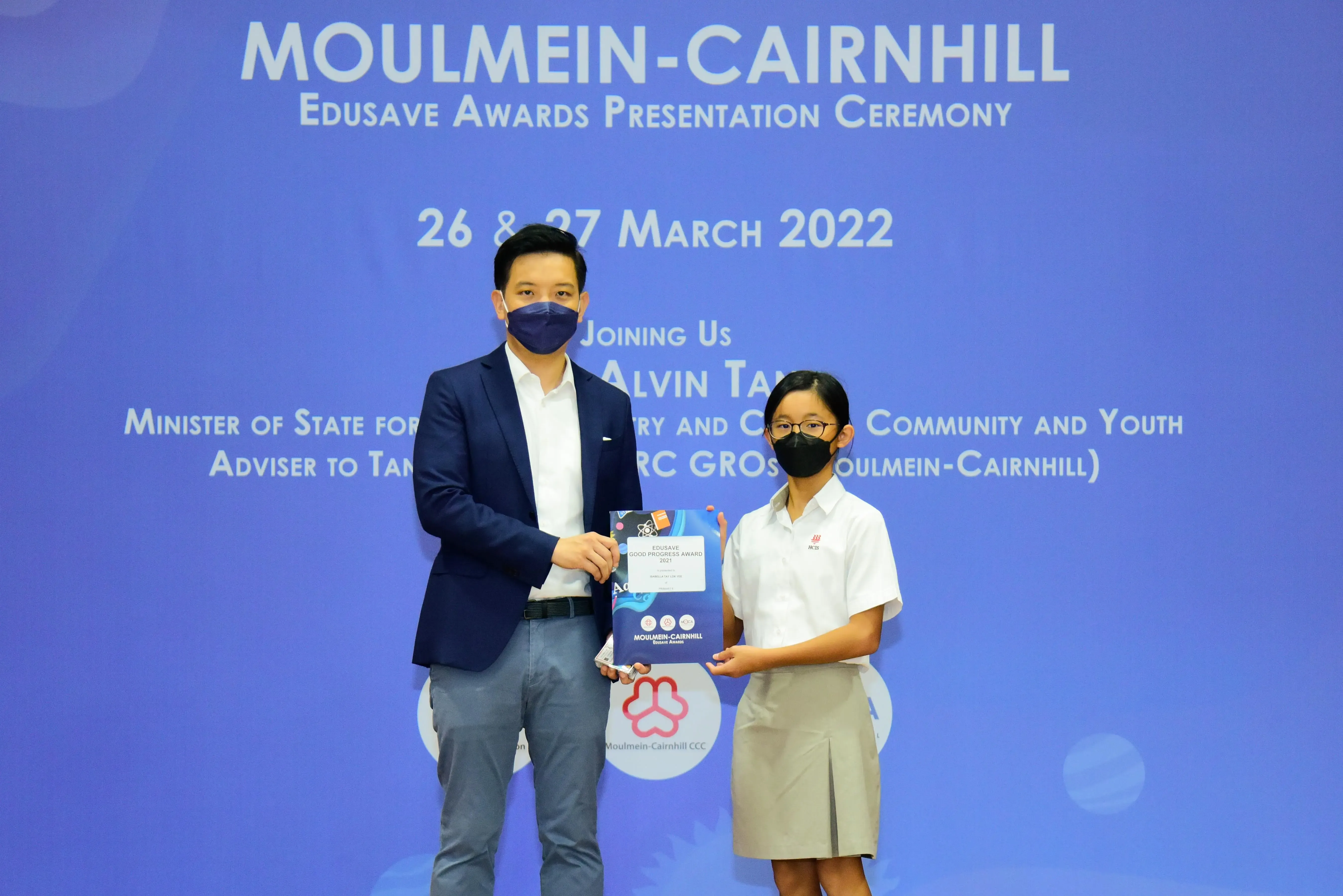 Two masked individuals hold an award booklet at the Moulmein-Cairnhill Edusave Awards Ceremony on March 26-27, 2022.
