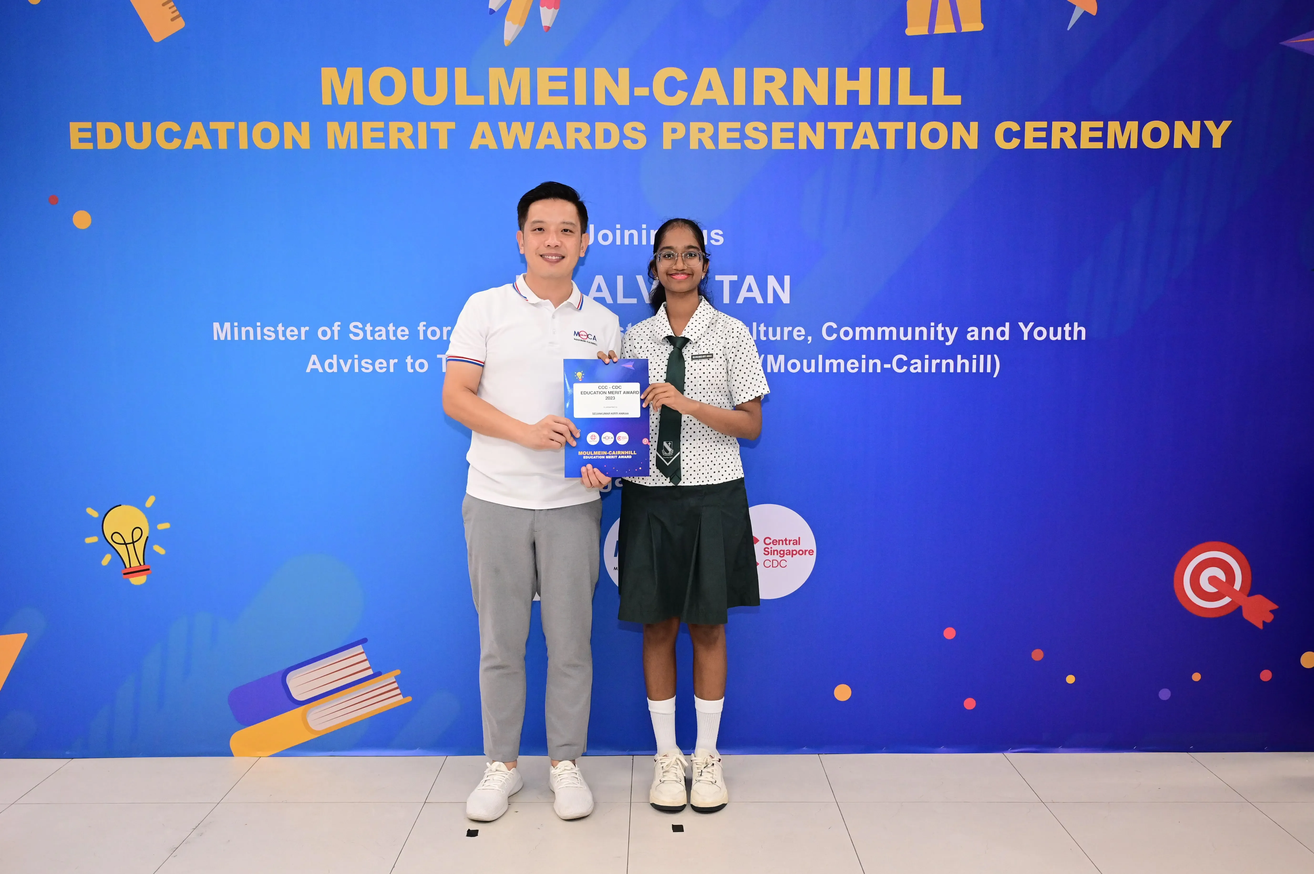 Two people hold an award booklet at the Moulmein-Cairnhill Education Merit Awards Presentation Ceremony.