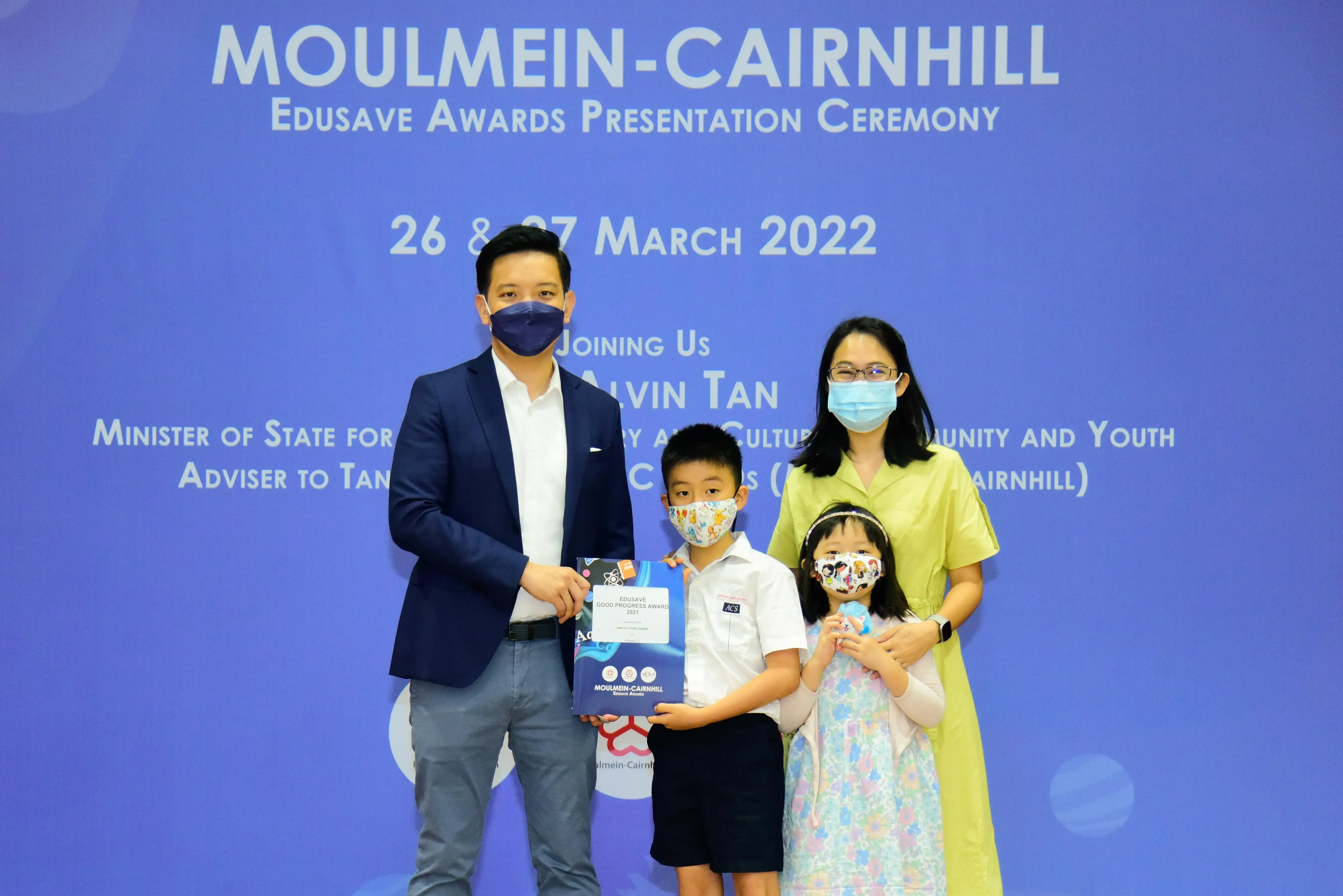 Four masked people pose at the Moulmein-Cairnhill Edusave Awards Presentation Ceremony on 26-27 March 2022.