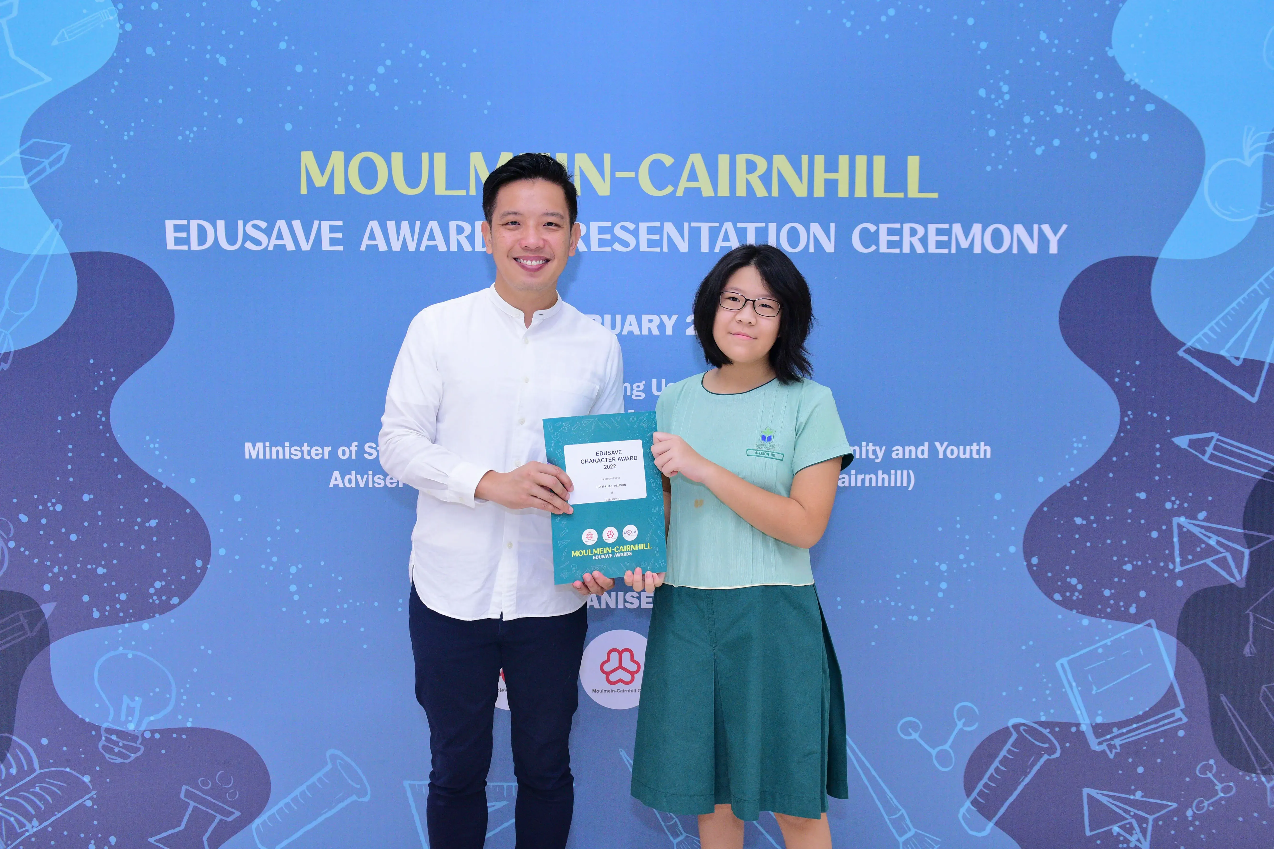 A man and a young girl hold an Edusave Character Award certificate at the Moulmein-Cairnhill Award Presentation Ceremony.