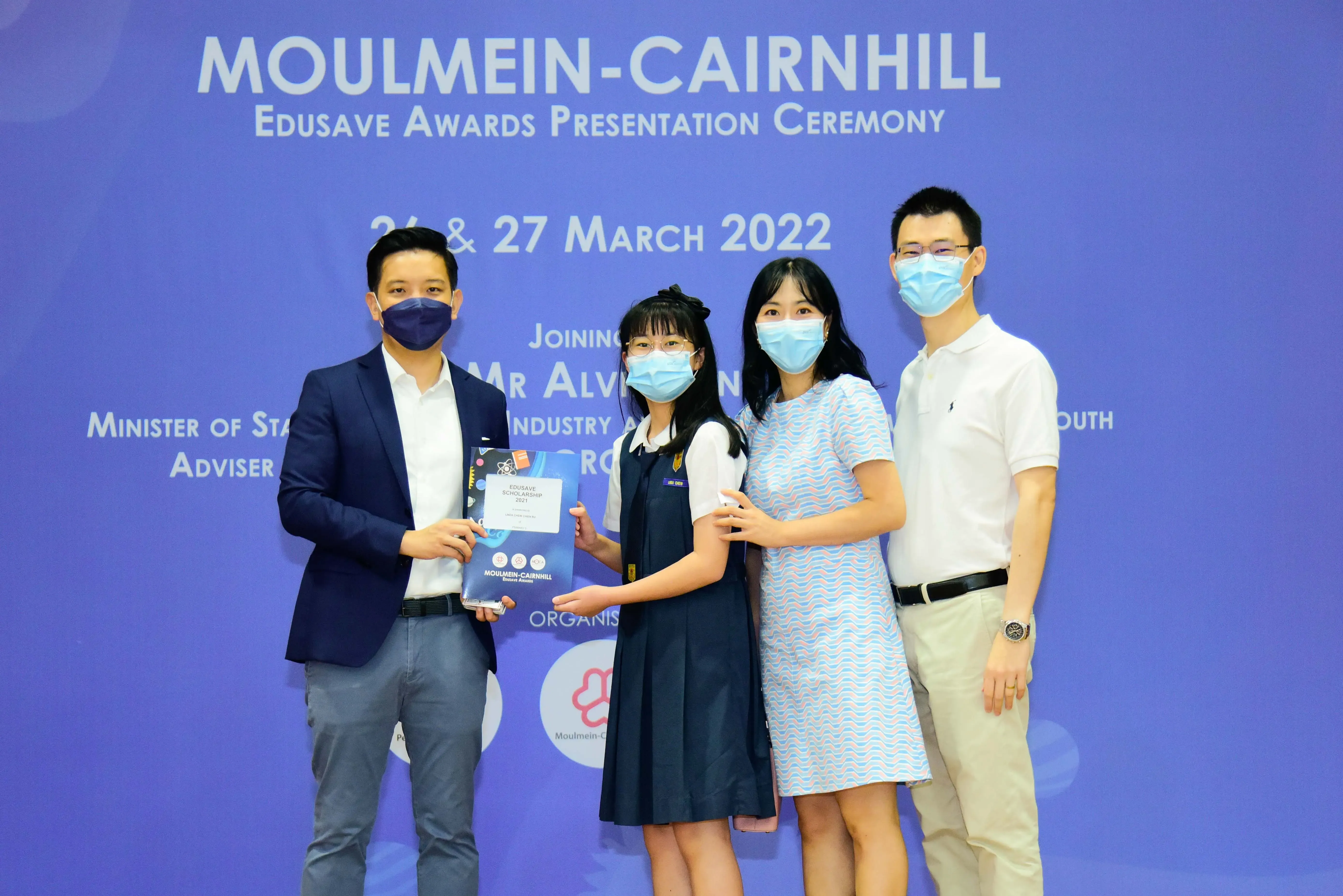Four masked people pose at the Moulmein-Cairnhill Edusave Awards Presentation Ceremony on 26-27 March 2022.