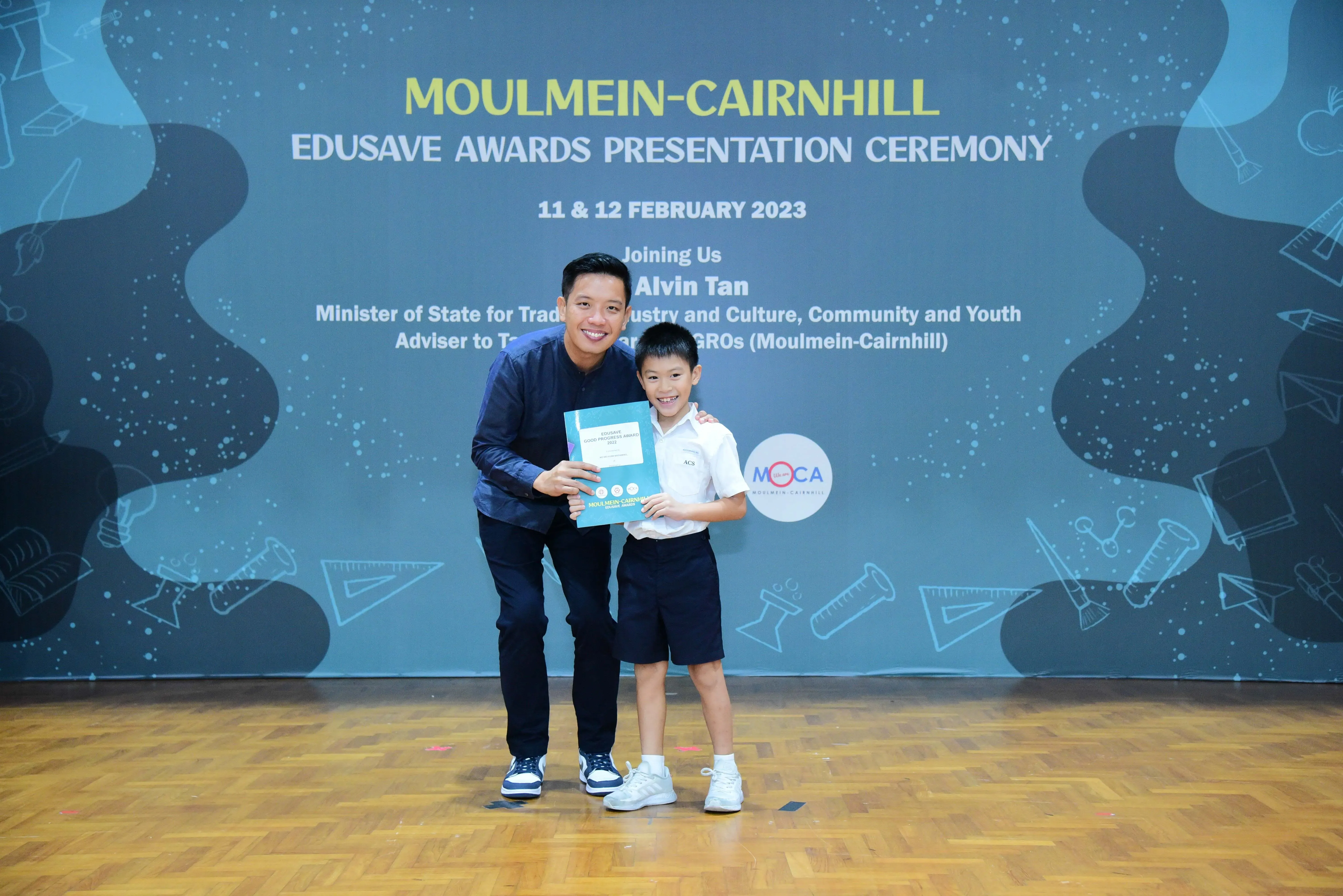 A man and a young boy hold a certificate together at the Moulmein-Cairnhill Edusave Awards Presentation Ceremony 2023.