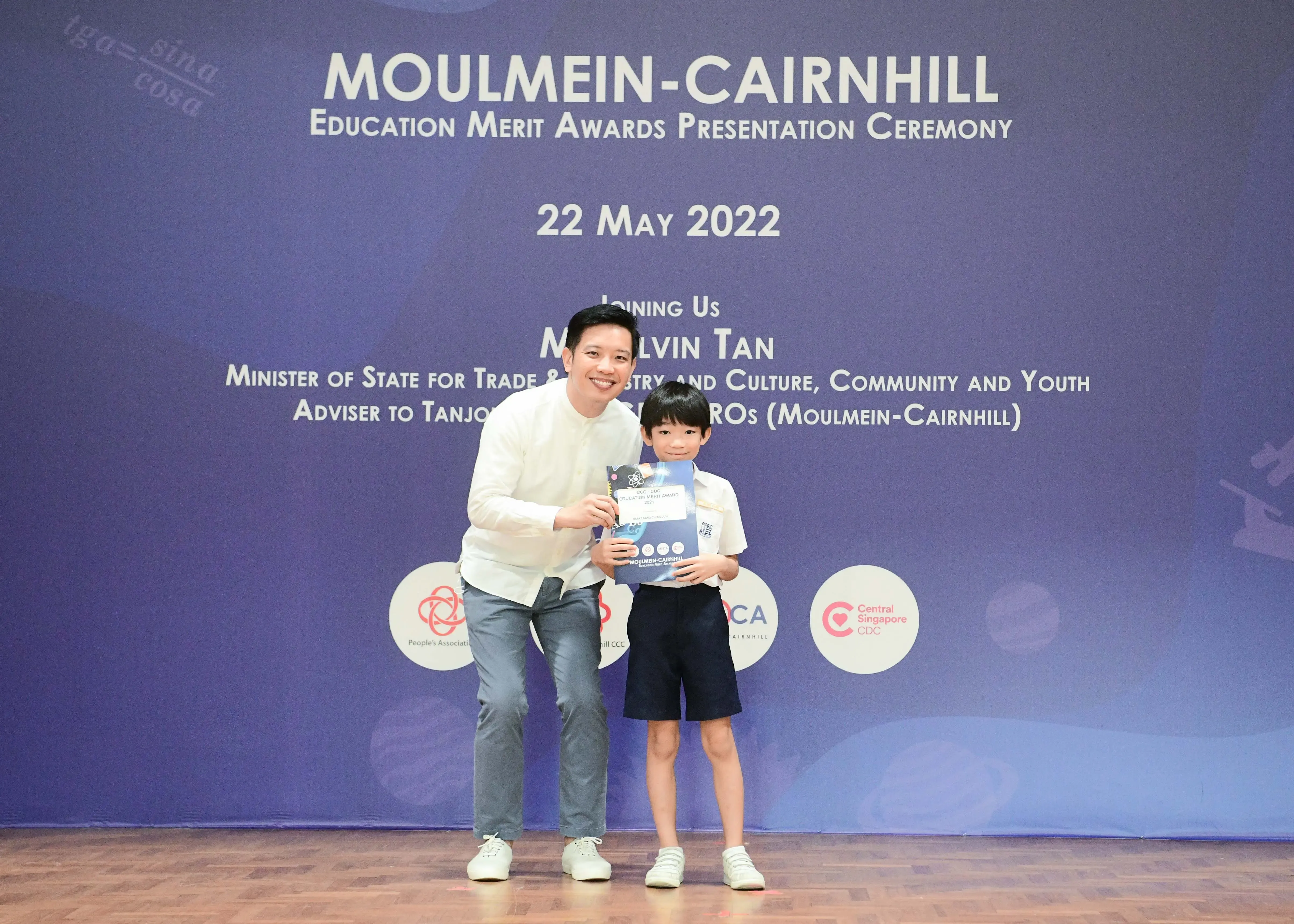 A man and a young boy hold an award certificate at the Moulmein-Cairnhill Education Merit Awards on 22 May 2022.